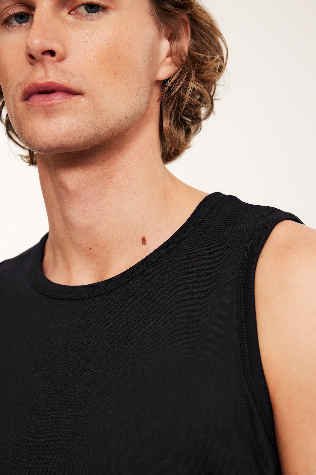 Zbliżenie na mężczyznę w jednolitym czarnym bawełnianym podkoszulku z prążkowaniem 1x1.