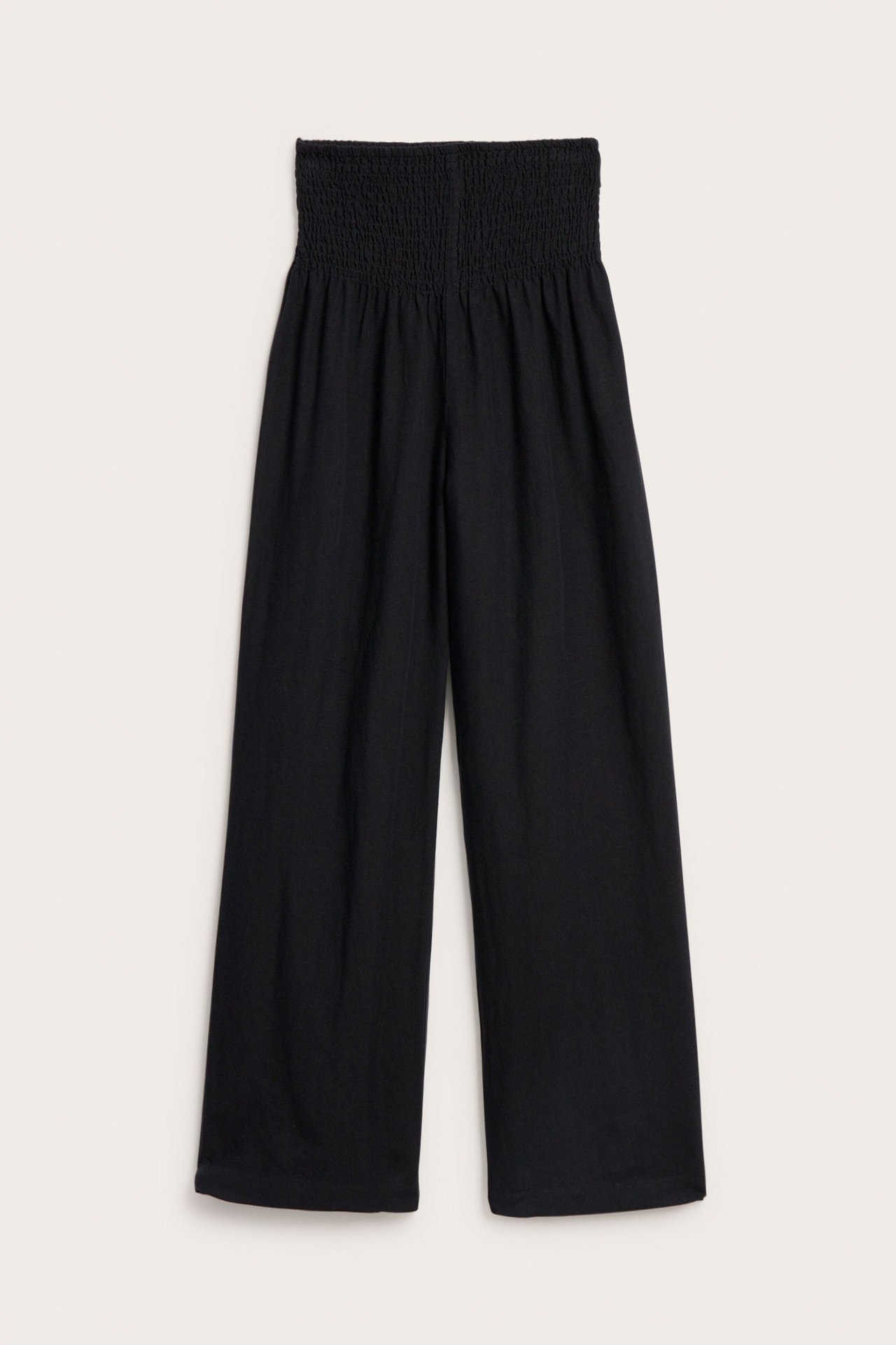 Edestä näkymä mustista, leveälahkeisista pellavasekoitehousuista, joissa smokkirypytys vyötäröllä.