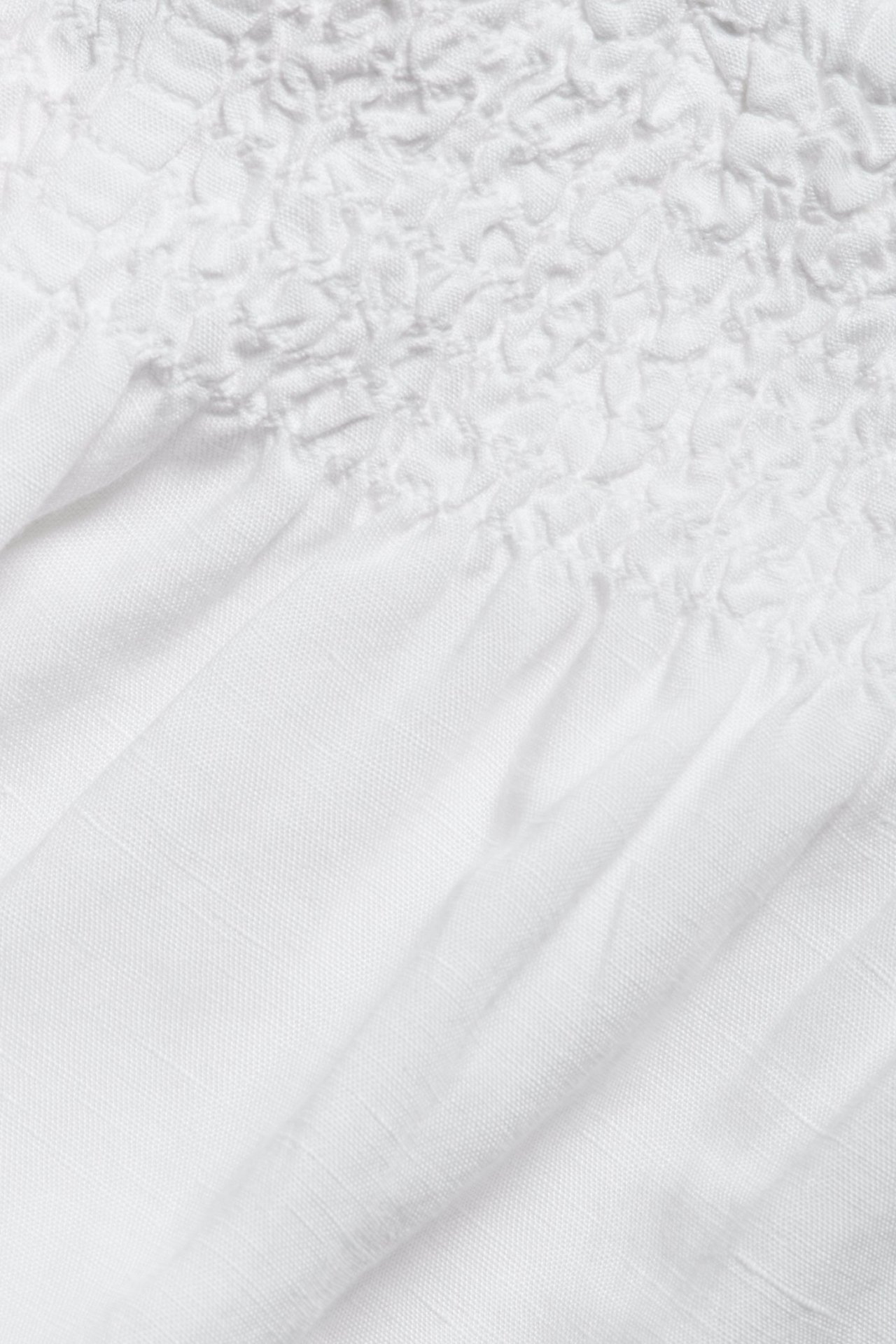 Zbliżenie białych szortów z mieszanki lnu ze ściągaczem w talii.