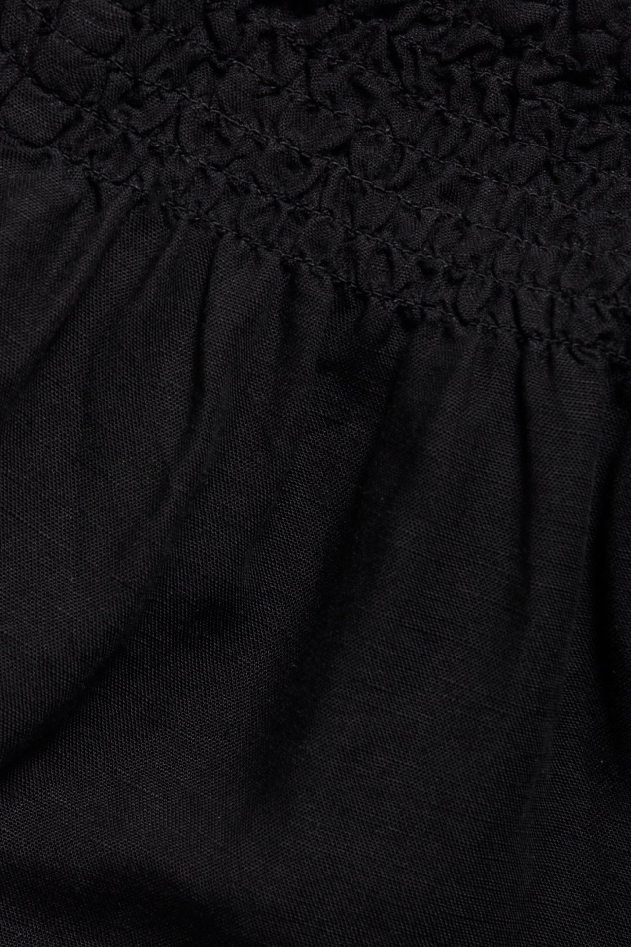 Zbliżenie na czarne szorty z mieszanki lnu ze ściągaczem w talii.