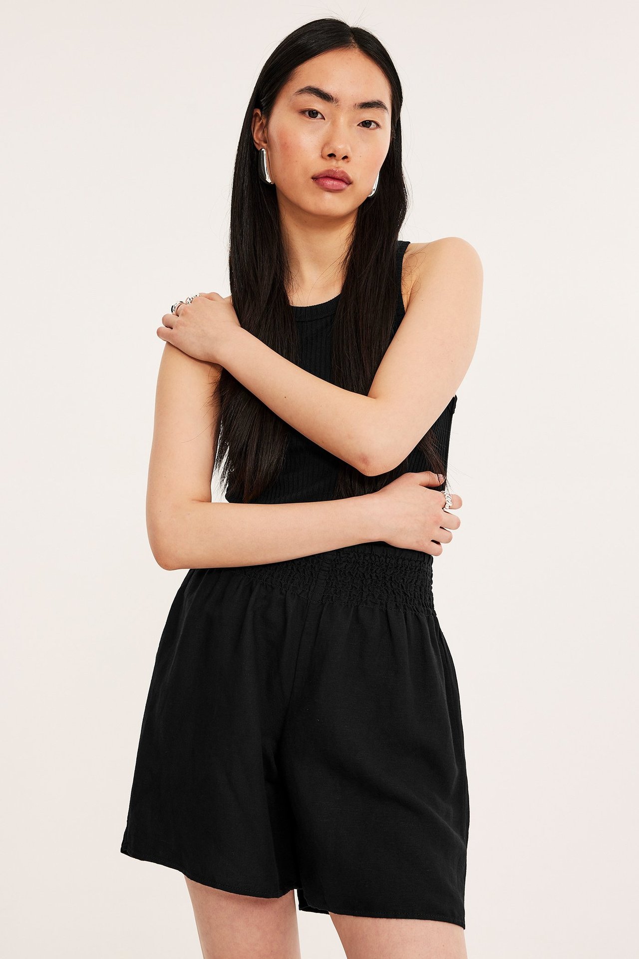 Widok z przodu: Kobieta w czarnych szortach z mieszanki lnu ze ściągaczem, czarny top w prążki.