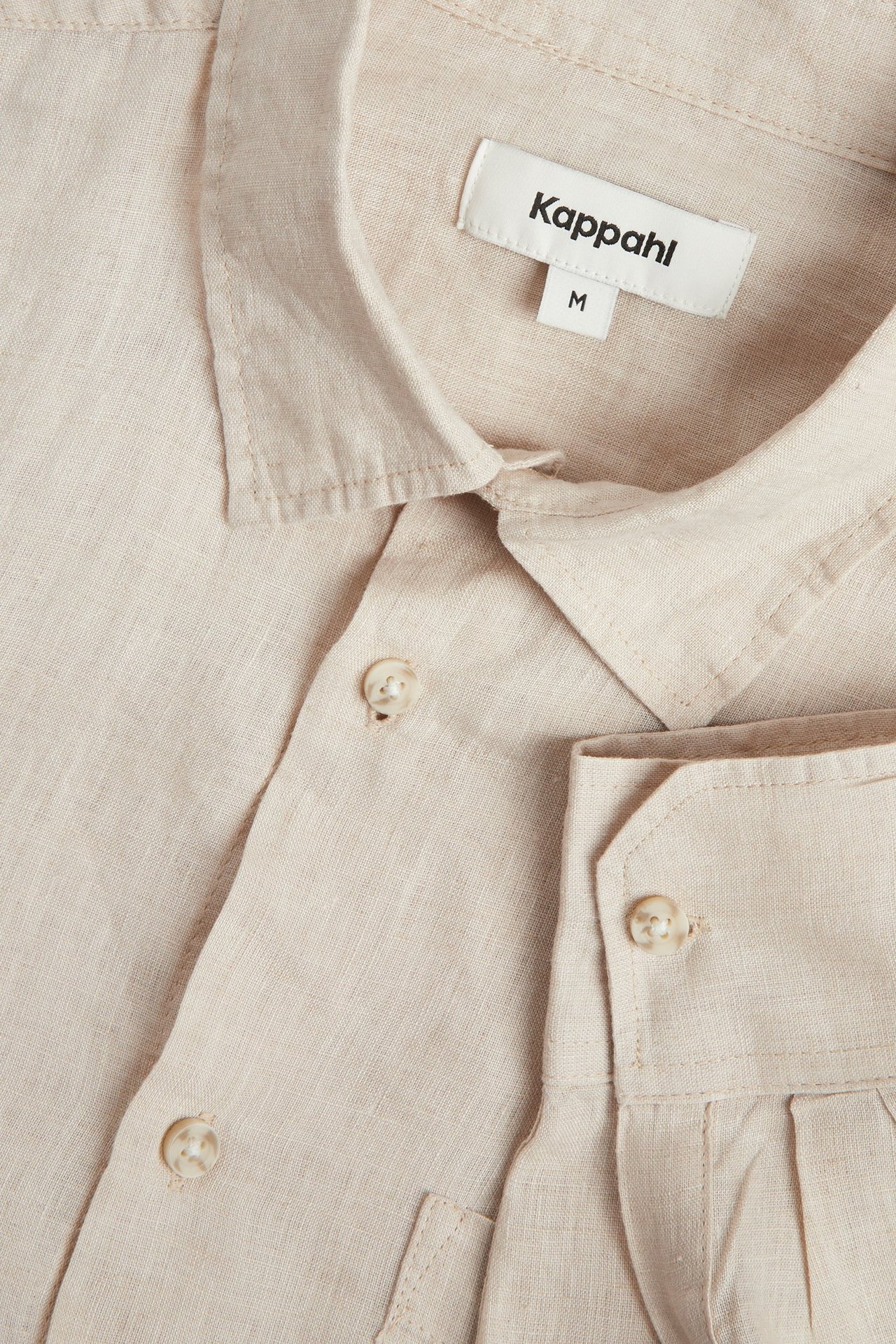 Lähikuva miesten beigestä pellavapaidasta, jossa on normaali kaulus ja napit edessä.