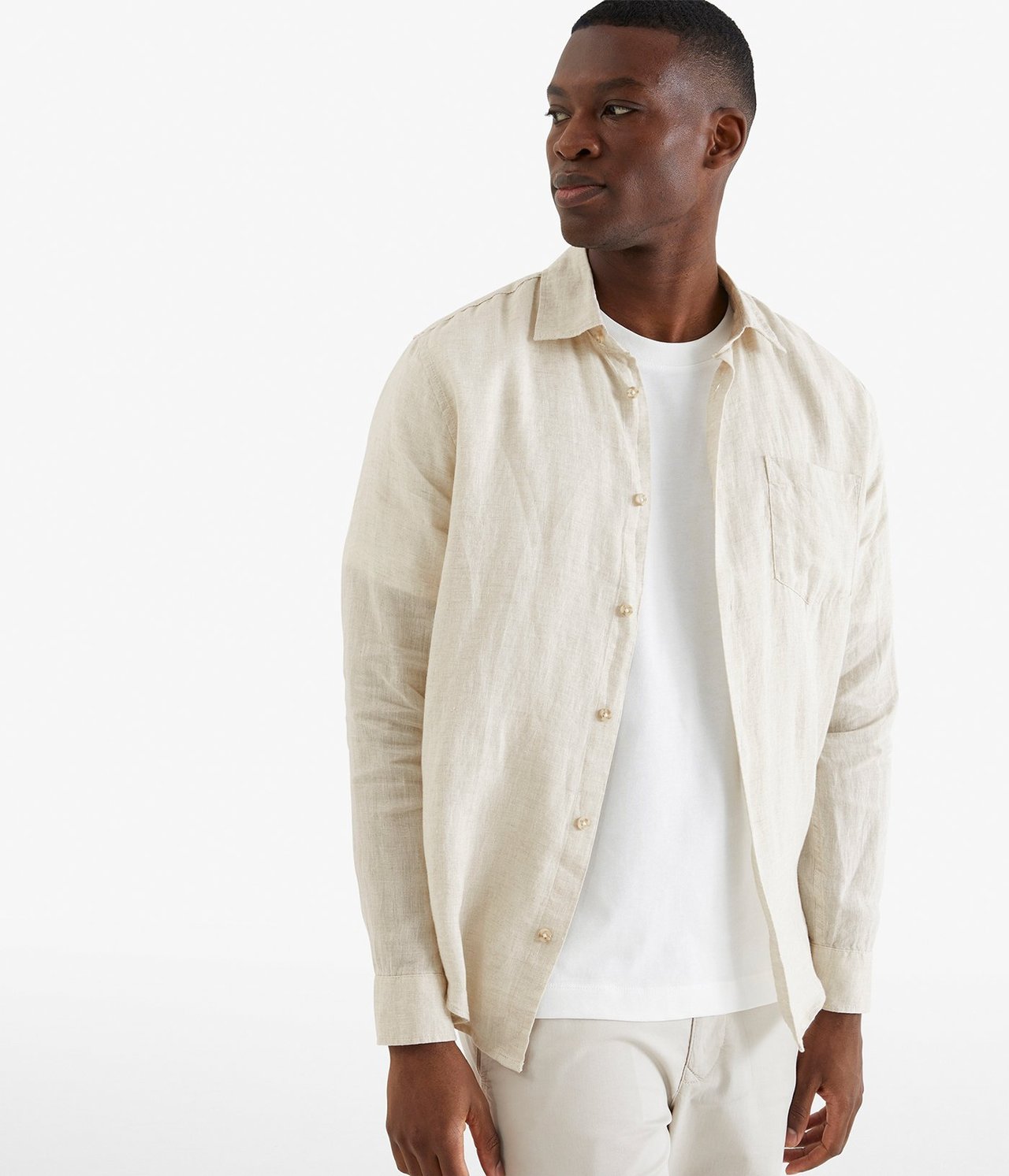 Edestä: Mies yllään beige melange pellavapaita, valkoinen t-paita ja beiget housut.