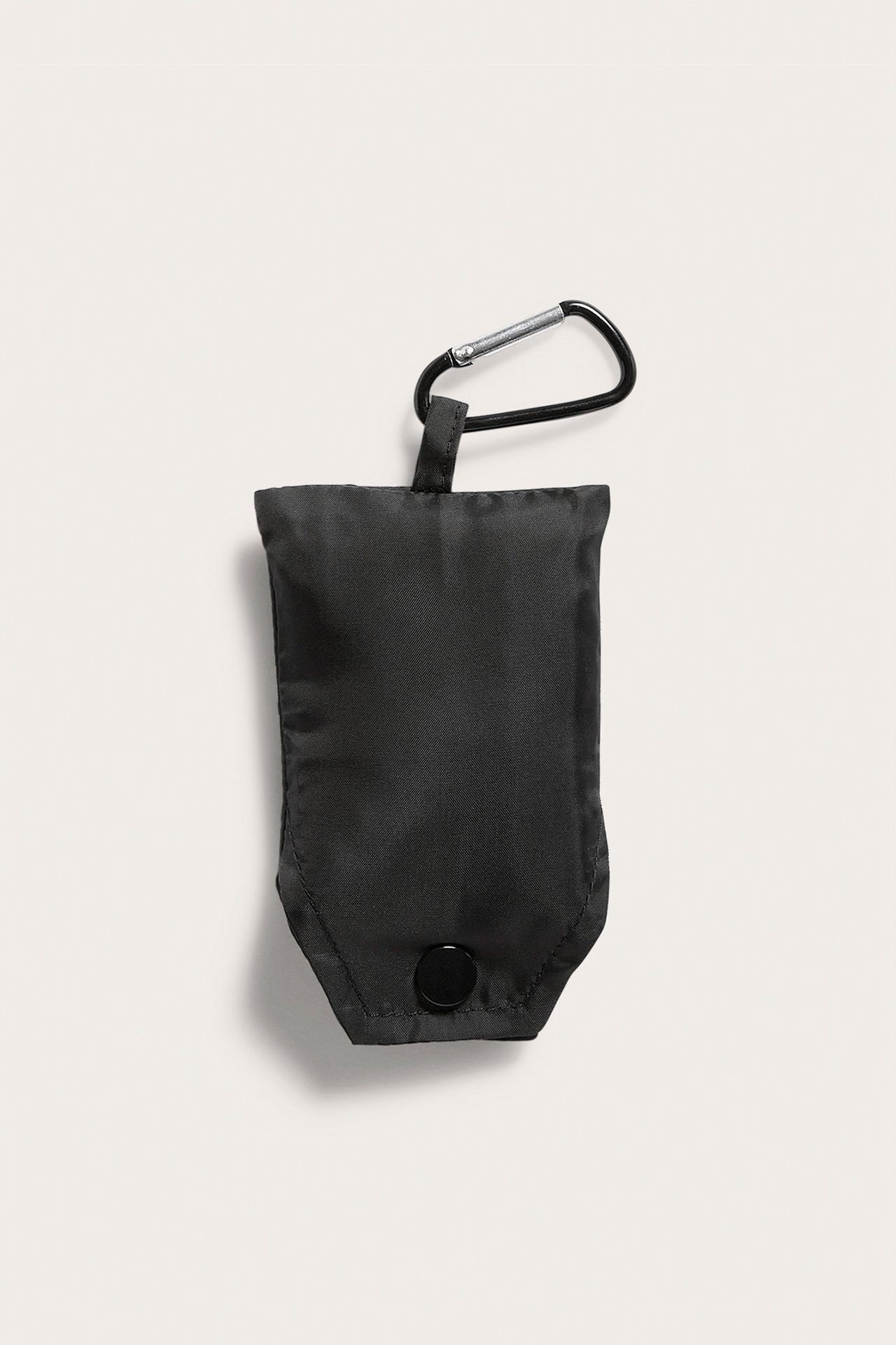 Framsida: Svart polyester shoppingväska hopfälld i liten påse med tryckknapp och karbinhake.