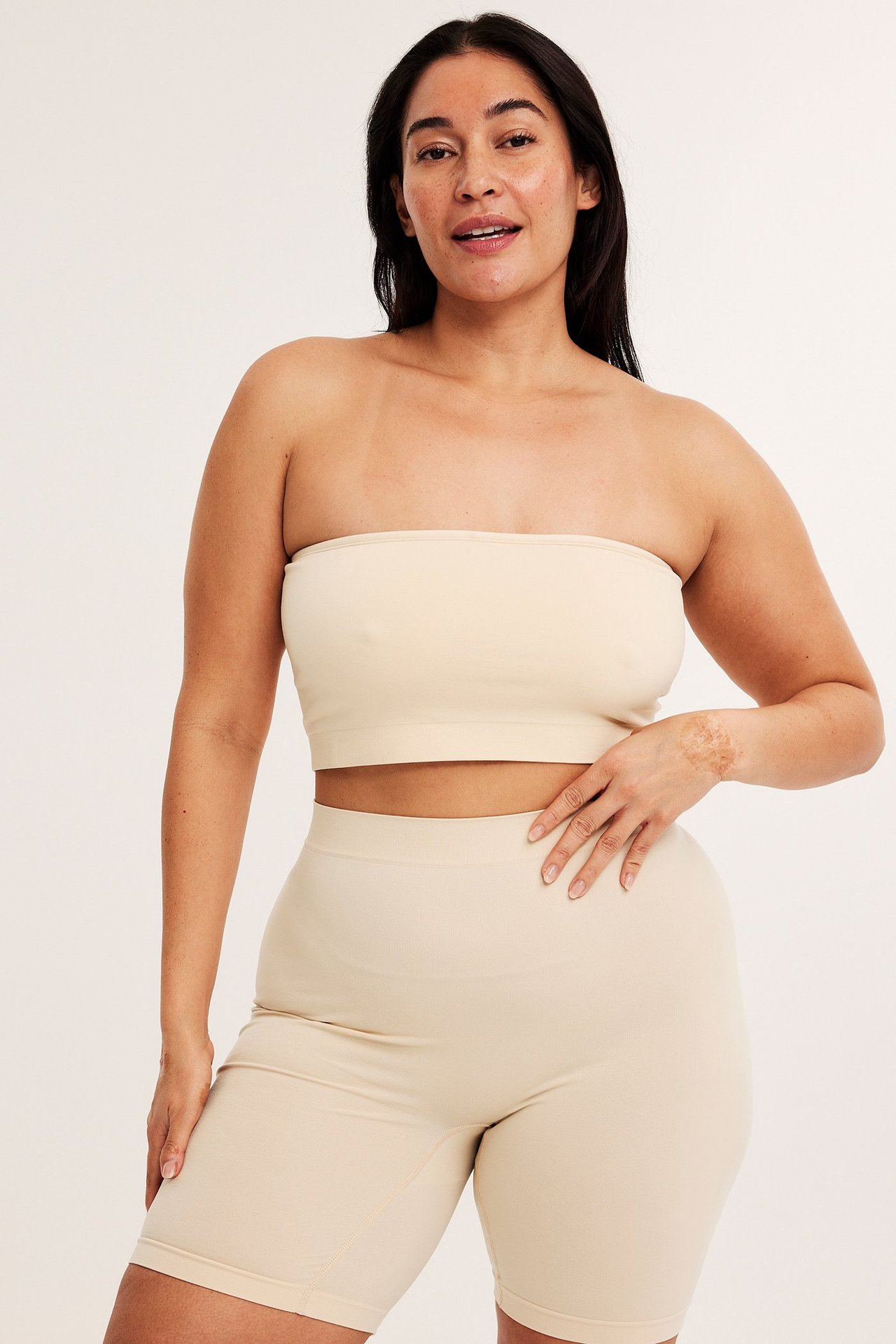 Forfra, kvinne i beige sømløse shorts og matchende bandeau-topp.