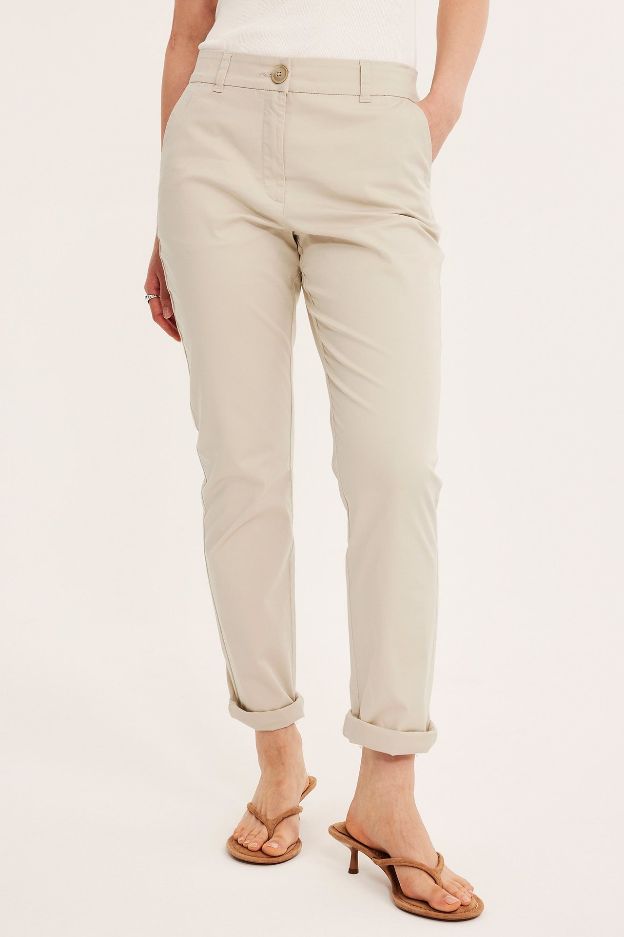 Frontvisning: Kvinne har på seg off-white stretch-bomullschinos, oppbrettede, med hvit topp og brune hælsandaler.
