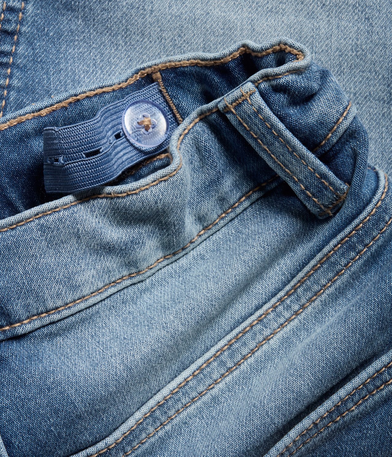 Nærbilde av lyseblå denimshorts linning med justerbar strikk og gjennomsiktig knapp.