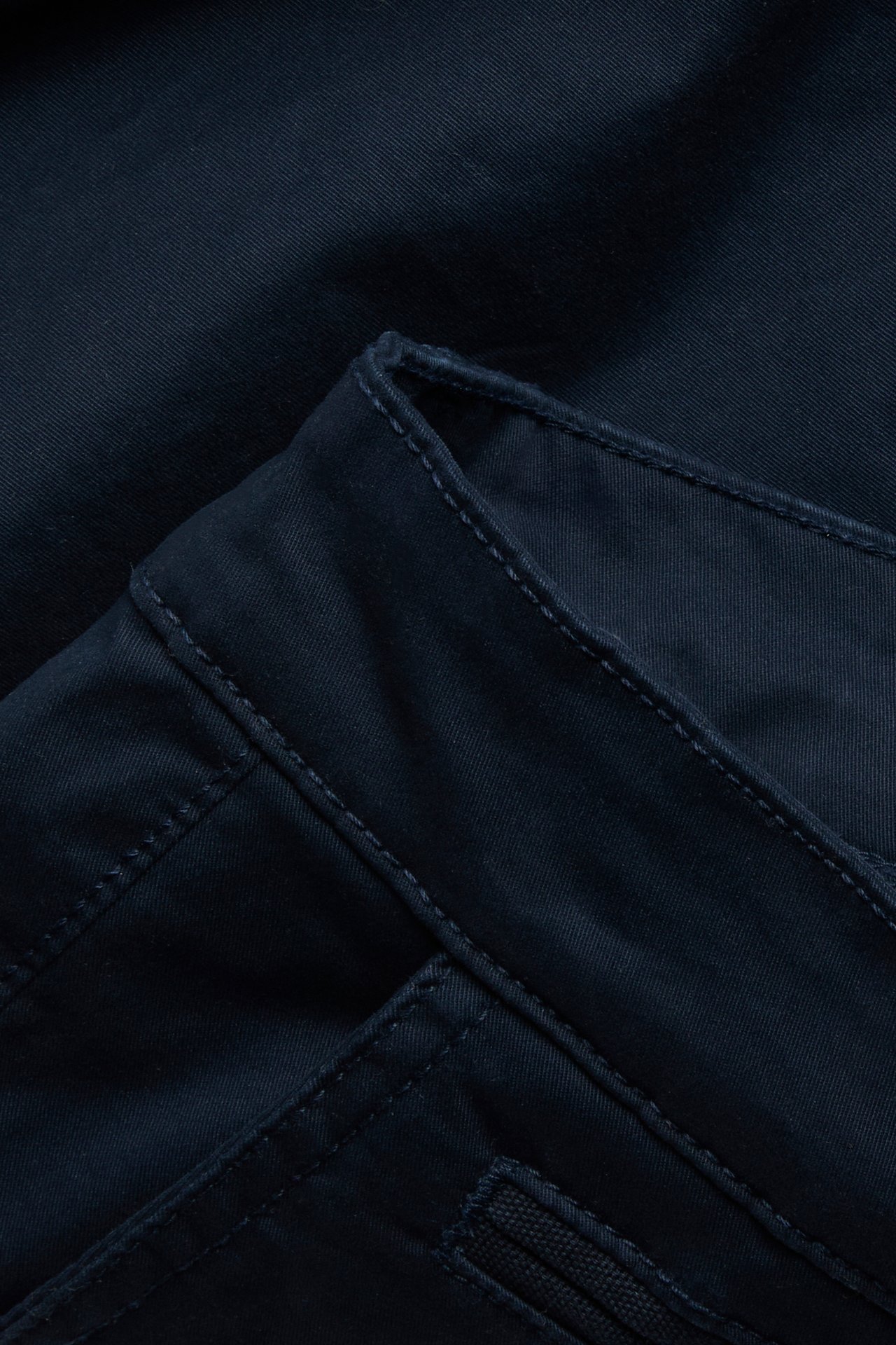 Närbild av mörkblå chinosshorts i bomullstwill för män, med synliga sömdetaljer.