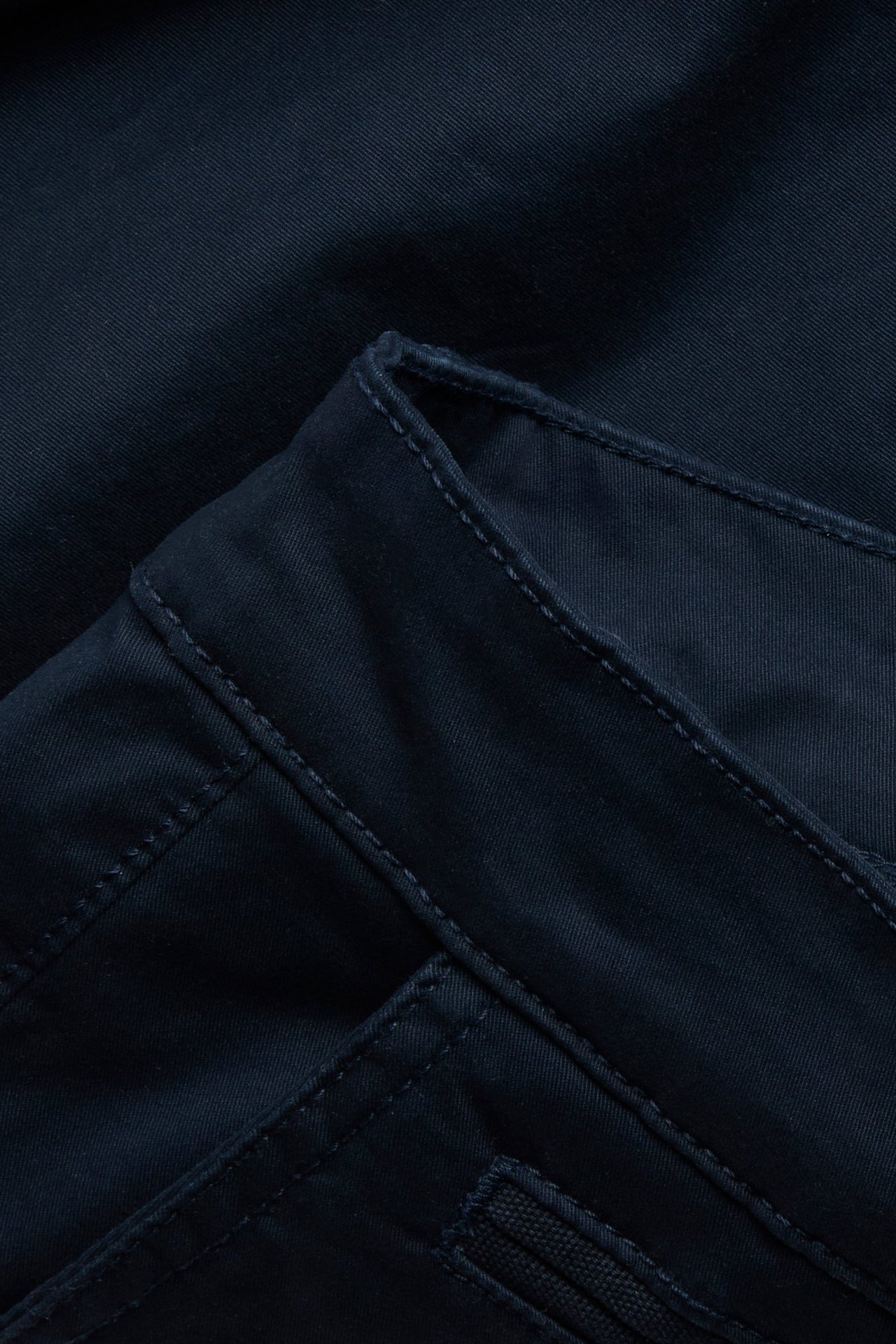 Zbliżenie na granatowe męskie szorty chino z bawełnianego twillu, z widocznymi szwami.