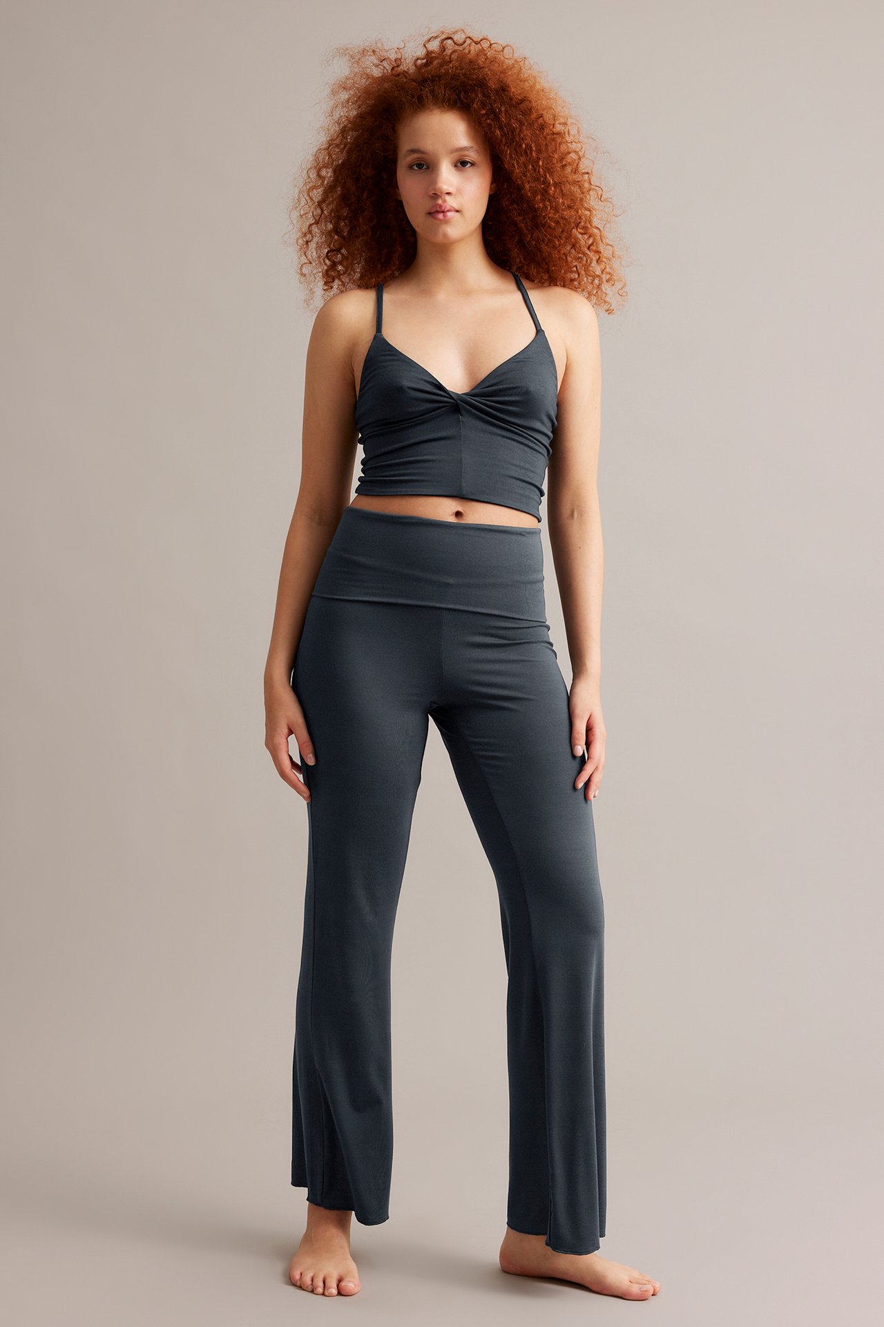 Edestäpäin nainen tummansinisissä bootcut-trikoohousuissa ja yhteensopivassa tummansinisessä trikootopissa.