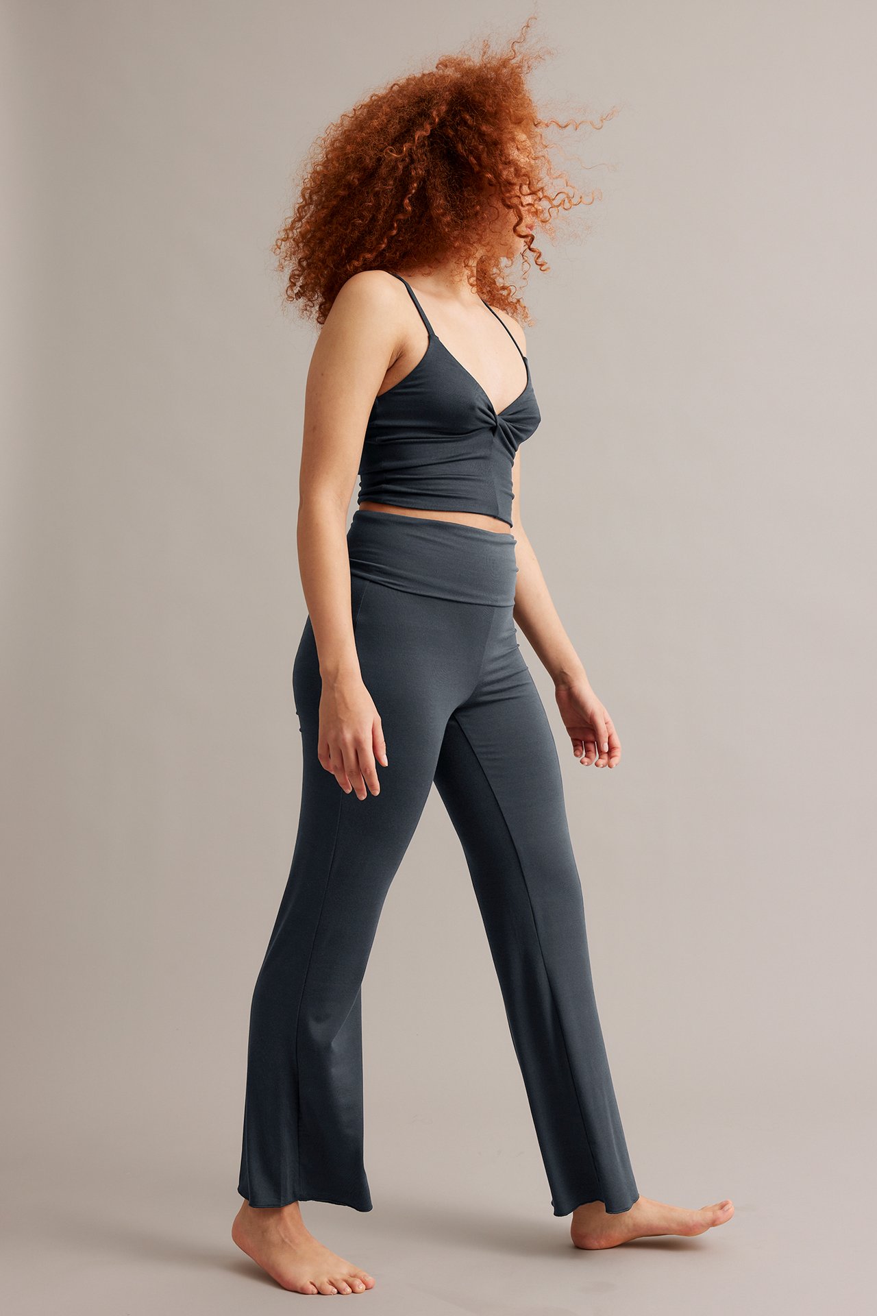 Sidebilde: kvinne i mørkeblå viskose bootcut-loungewearbukser med nedbrettbar midje og matchende croptop.