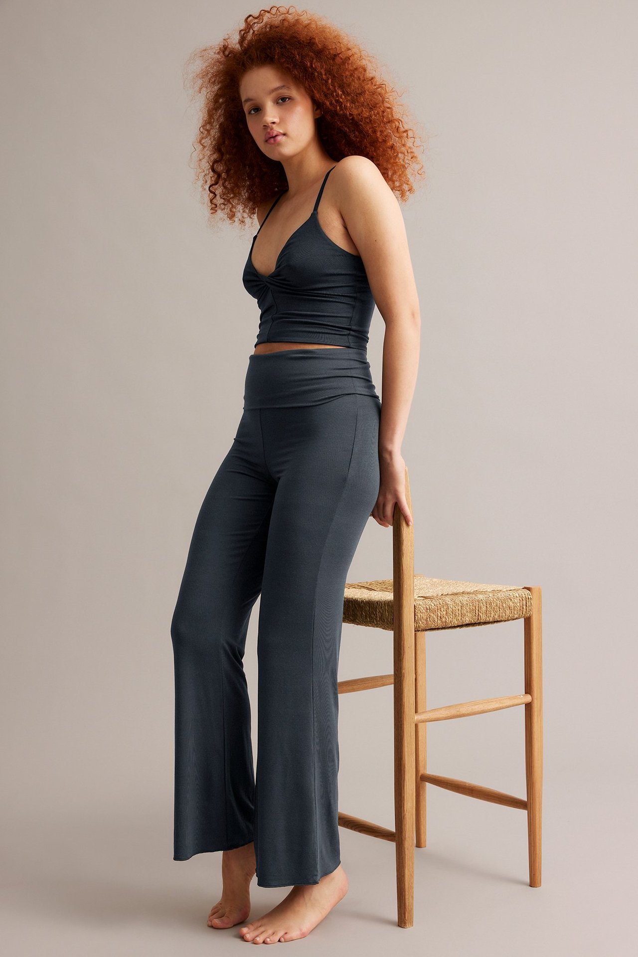 Nainen tummansinisissä bootcut-loungewear-housuissa taitettavalla vyötäröllä ja yhteensopivassa topissa.