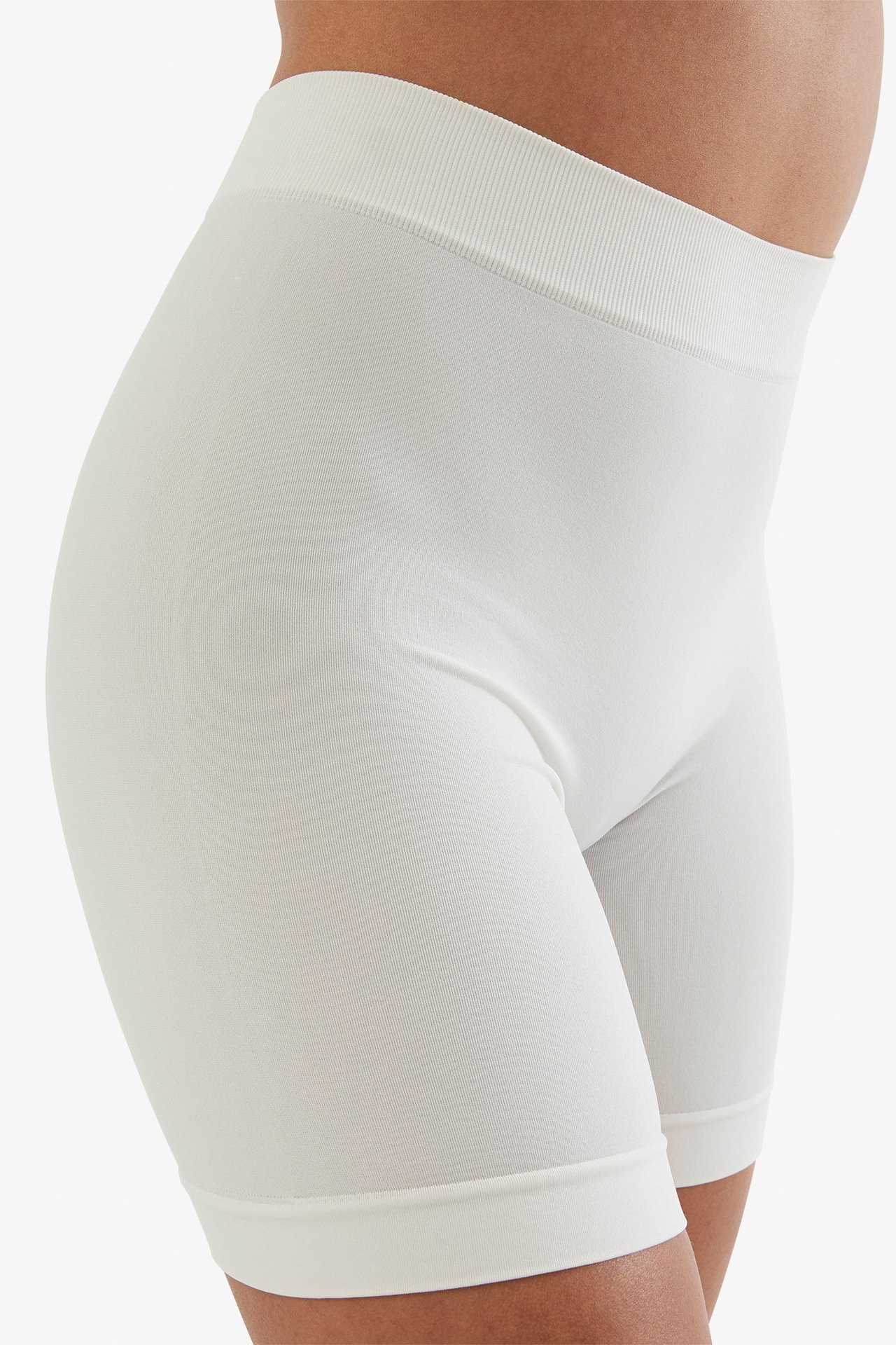 Sidovy av en kvinna som bär vita sömlösa shorts med hög midja.