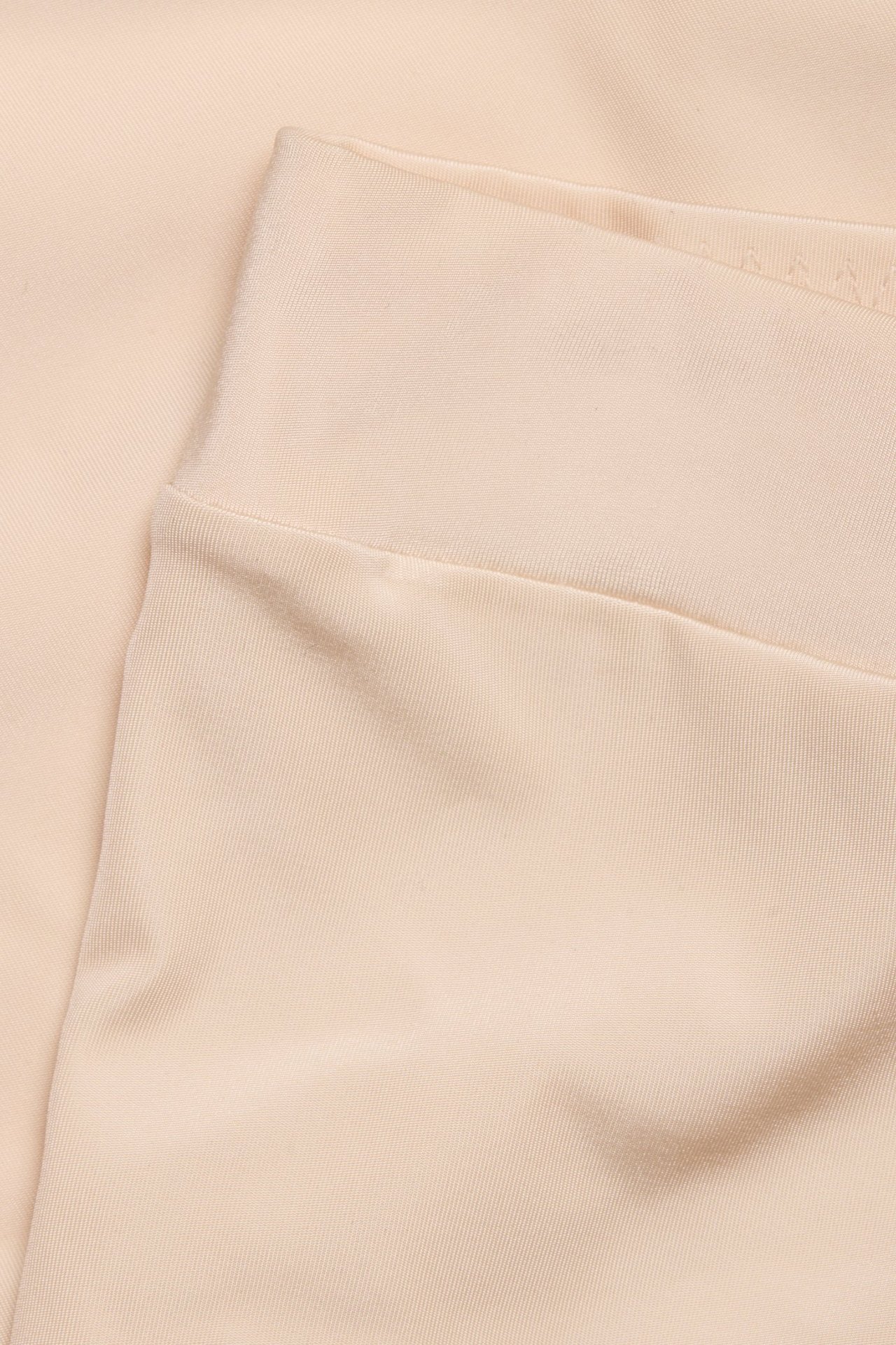 Zbliżenie beżowych szortów modelujących z miękkiego, elastycznego mikrowłókna.