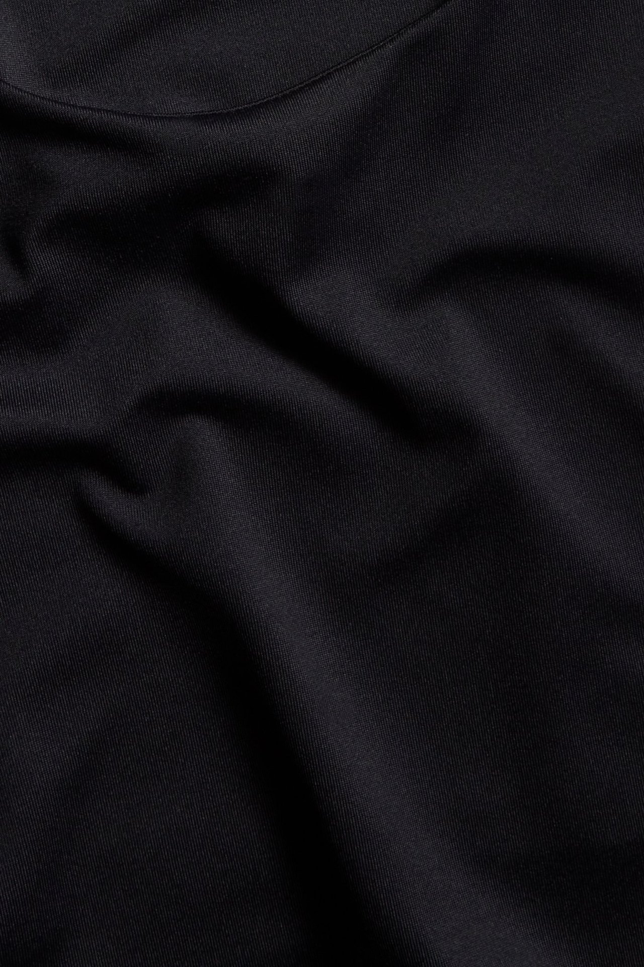 Zbliżenie czarnego, gładkiego, jednolitego materiału na obcisły top.