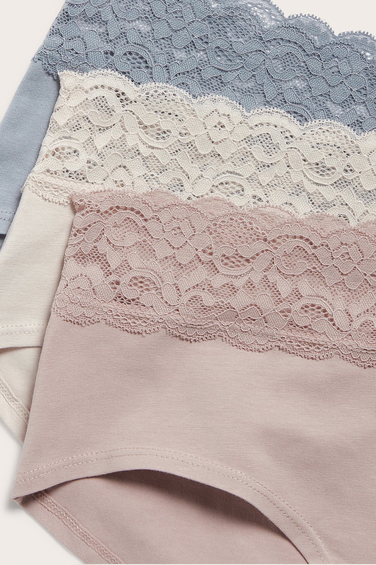 Zbliżenie trzech damskich fig hipster: różowych, beżowych i jasnoniebieskich, z koronkowym pasem.