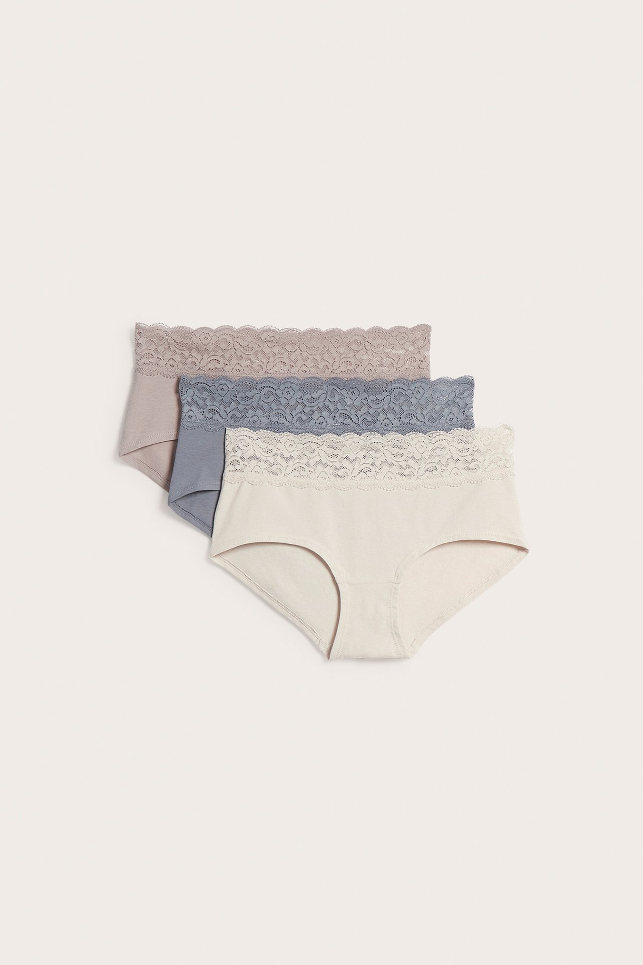 Frontvy av 3-pack enfärgade hipstertrosor i bomull i beige, blågrå och taupe med spetsmidjor.