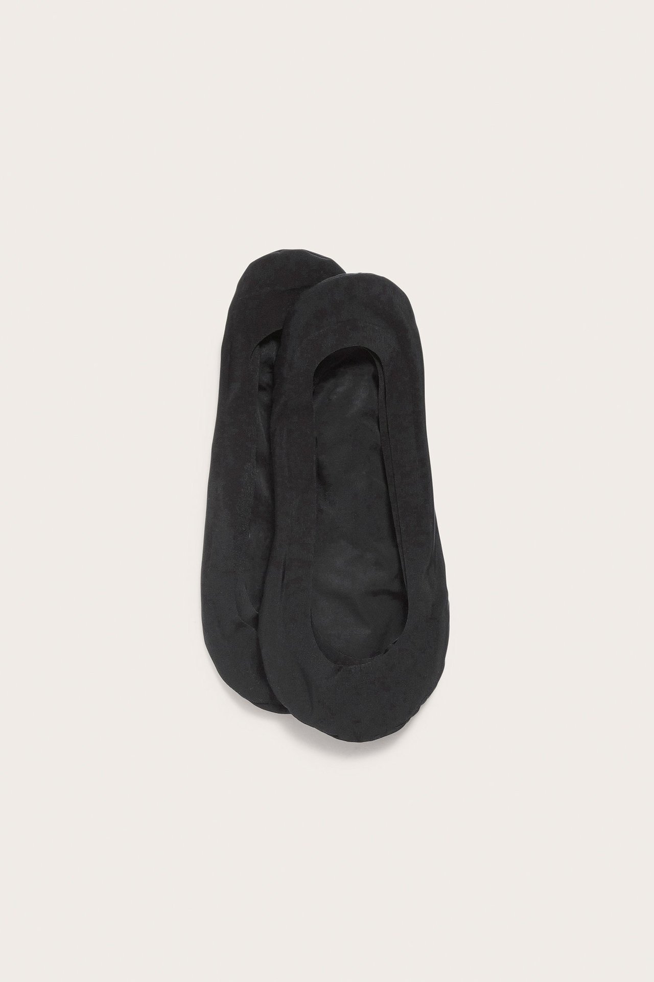 Widok z góry na dwie czarne, niskie stopki o prostym wzorze.