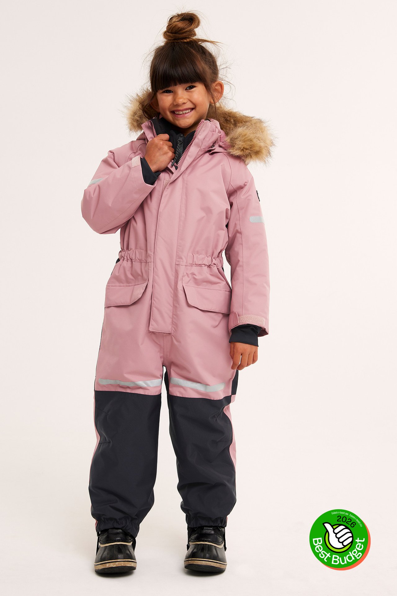 Framifrån, ett barn i rosa och mörkgrå overall med fuskpälskant och reflexdetaljer.