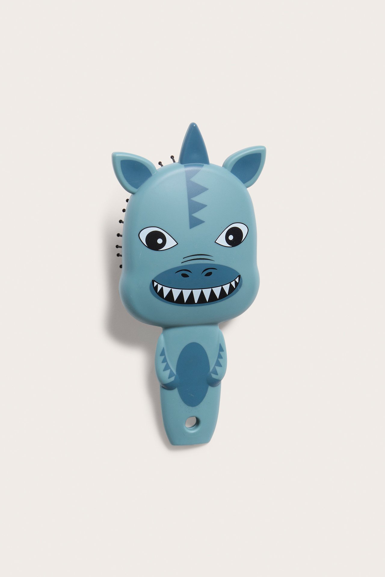 Frontvy av en blå plastdinosaurie-hårborste med svarta piggar och tecknade drag.