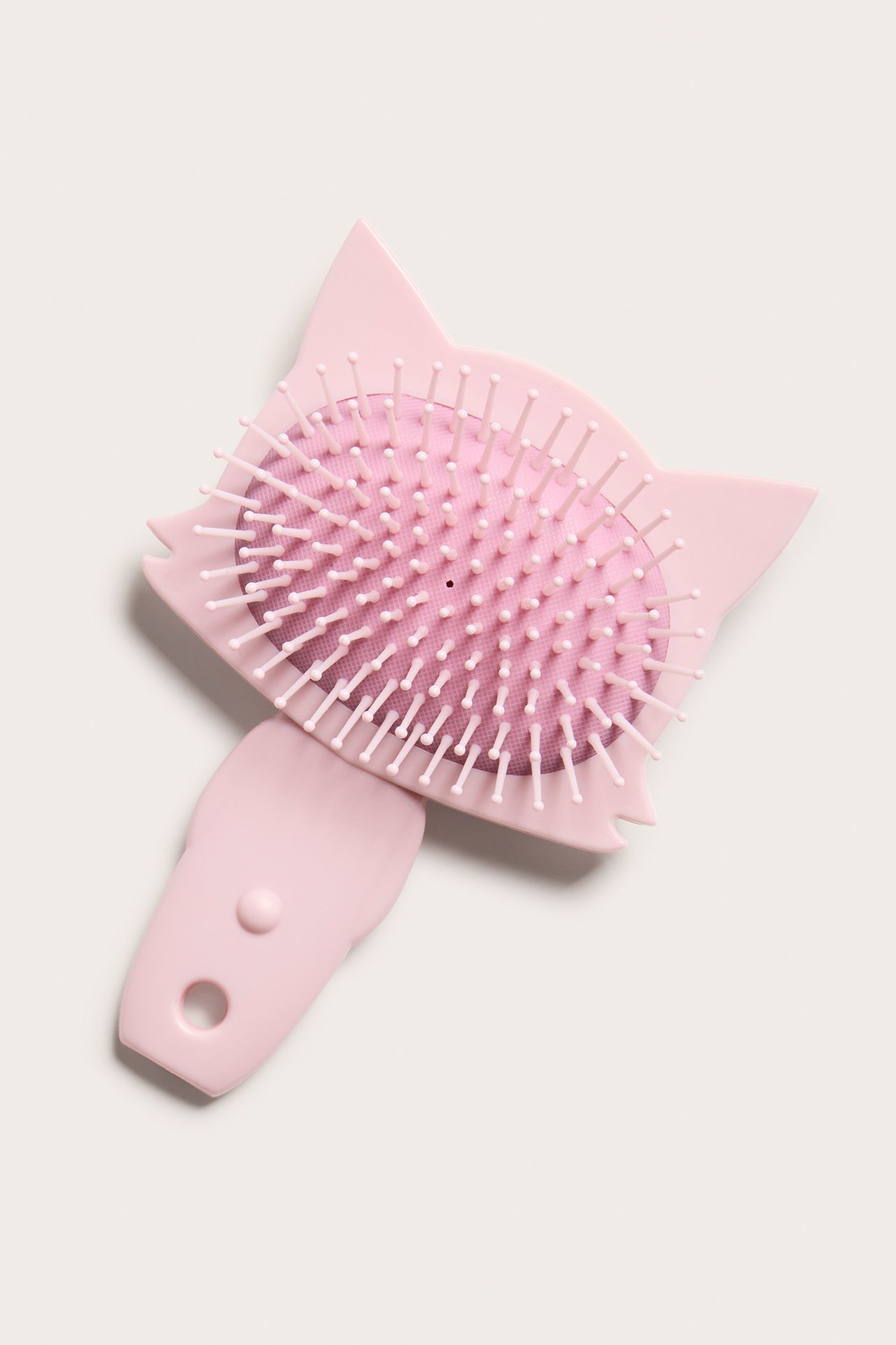 Toppvy av en rosa plast-hårborste formad som en katt med vita piggar.