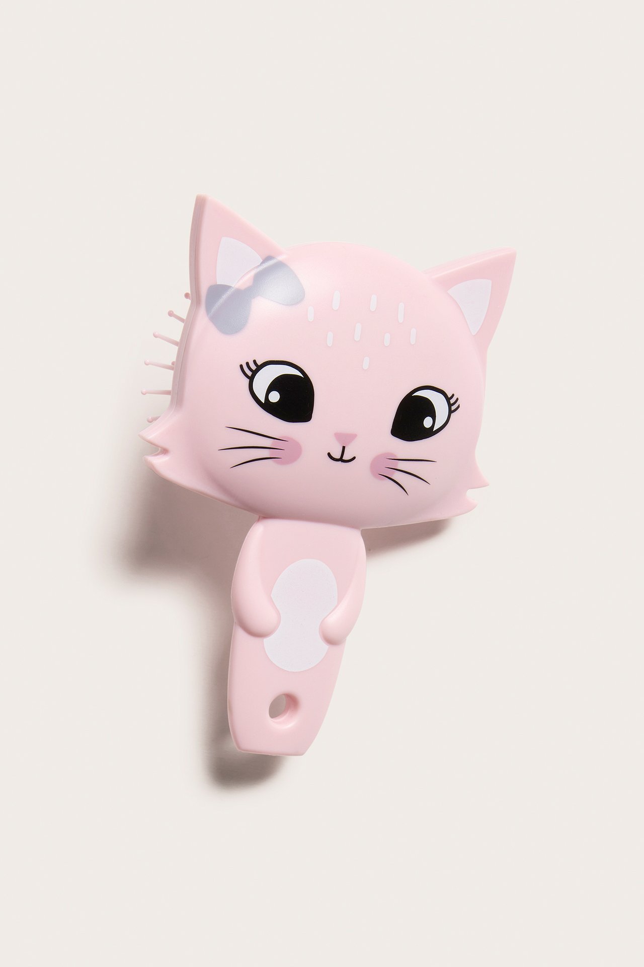 Framifrån, rosa hårborste i plast formad som en katt med vita detaljer och svarta ansiktsdrag.