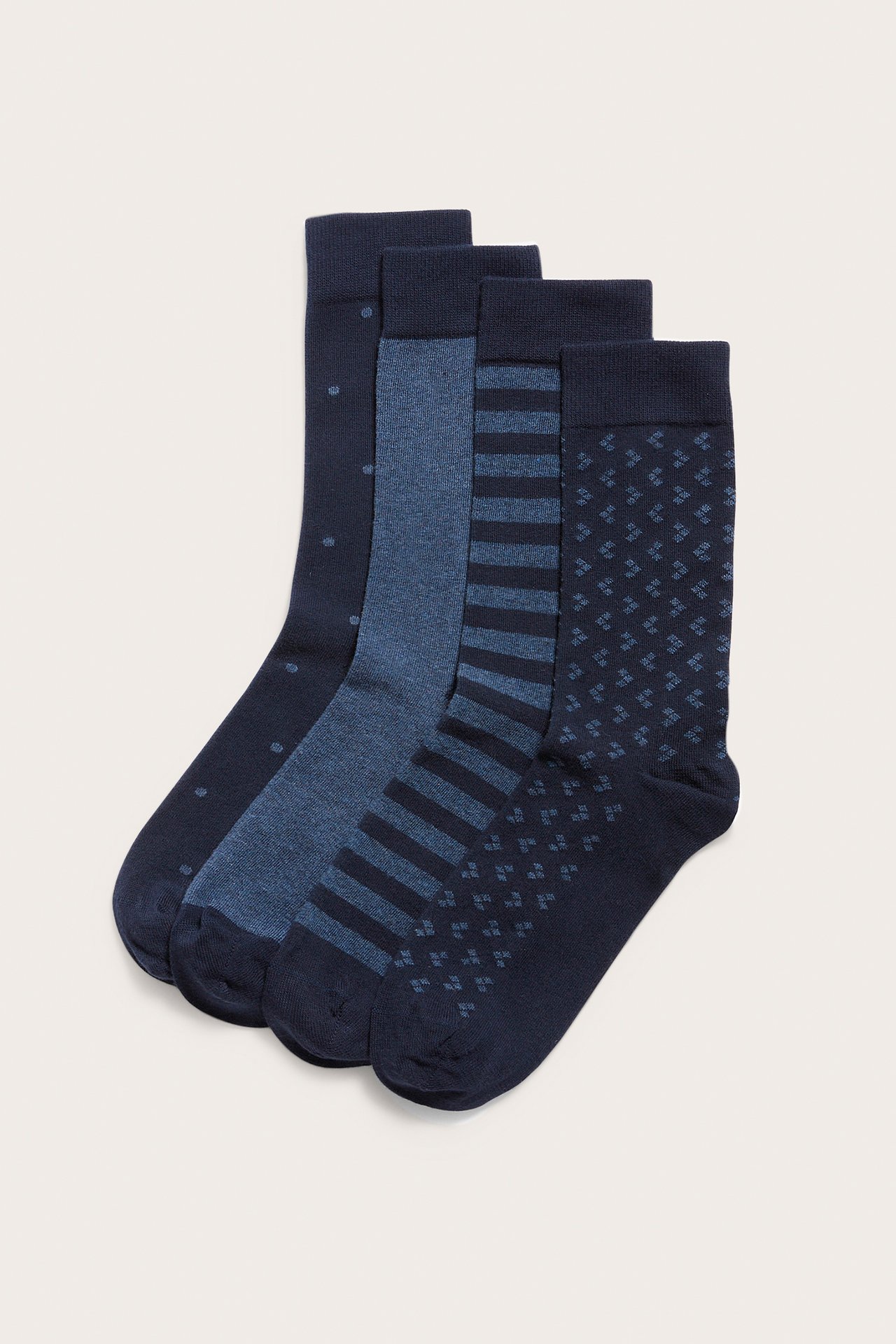 Etunäkymä neljän pakkauksen sinisiä puuvillasekoitesukkia, jokaisessa eri kuvio.