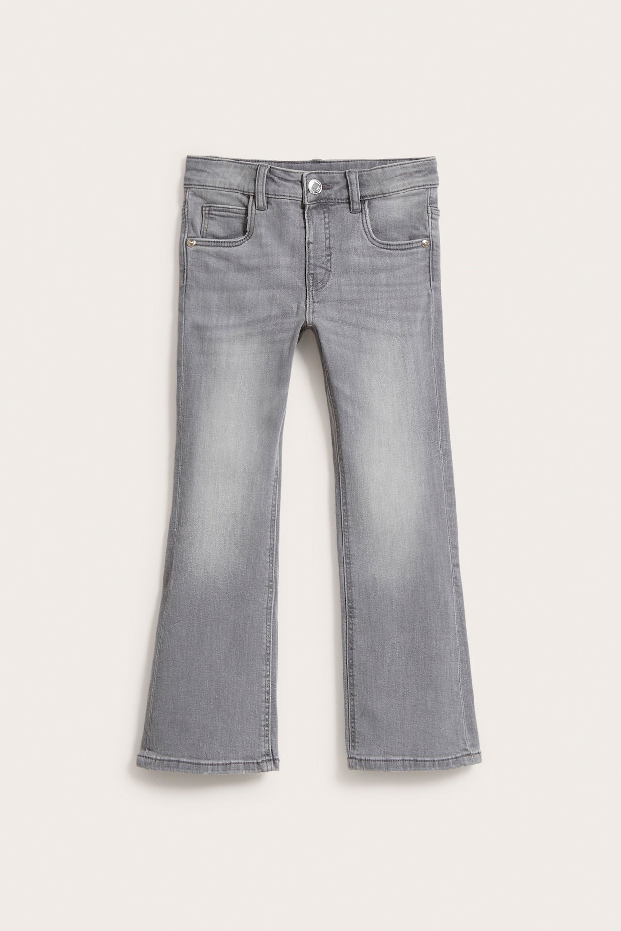 Edestä näkymä lasten harmaista bootcut-farkuista joustavaa denimiä, vyötäröllä painonappi.
