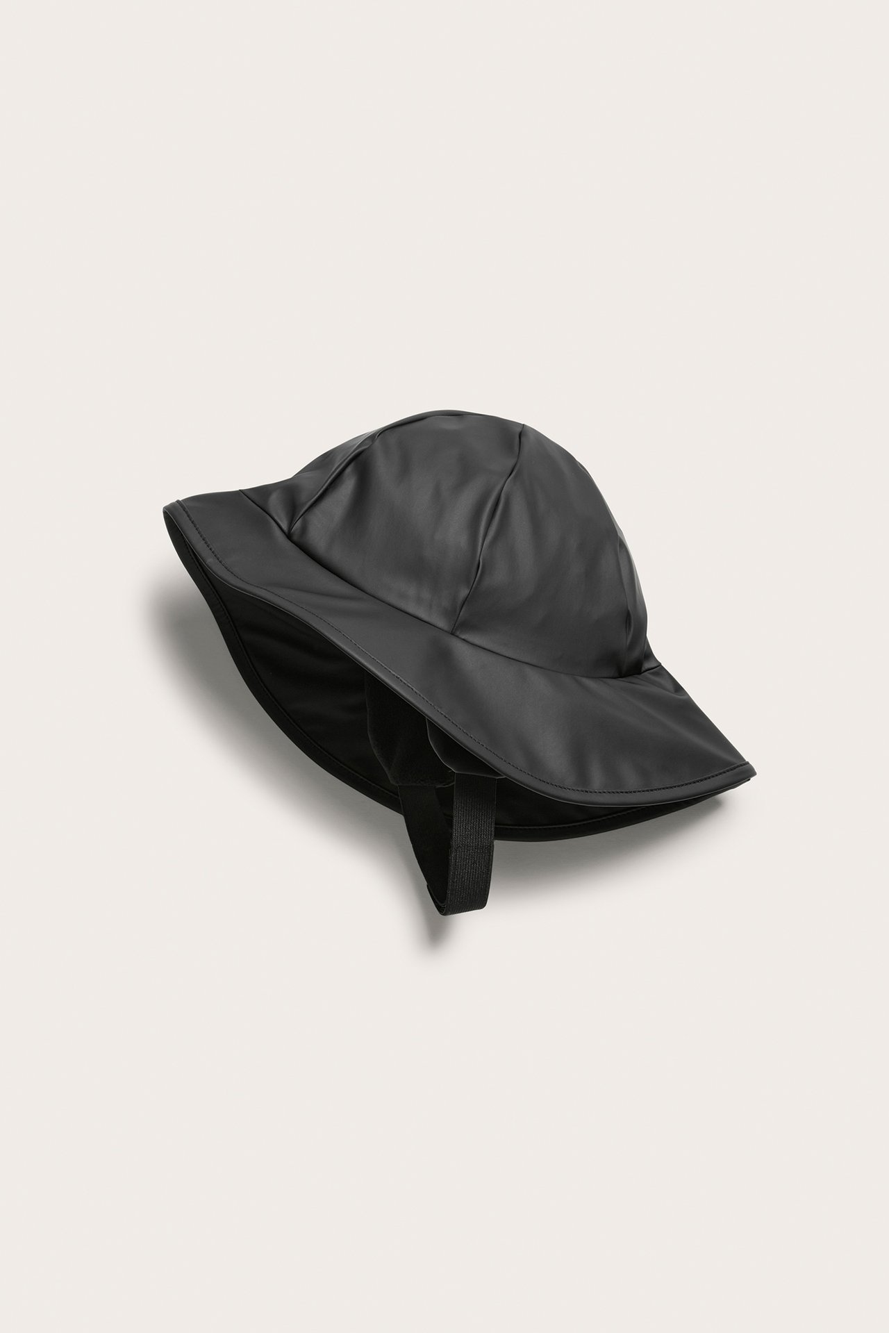 Sidovy av en enfärgad svart regnhatt för barn i återvunnen polyester med hakband.