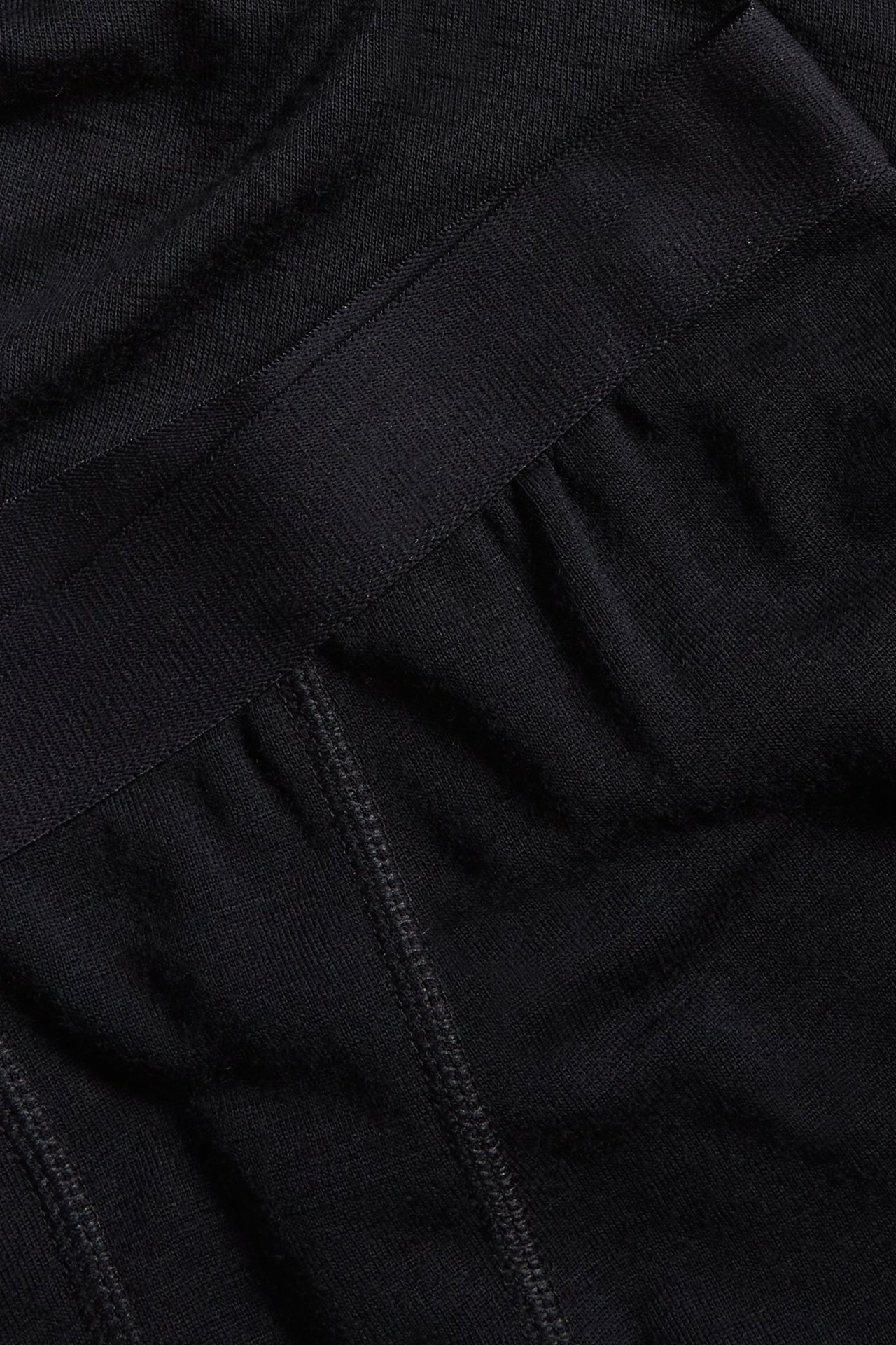 Zbliżenie na czarne kalesony z wełny merynosów, ukazujące fakturę materiału i pas.