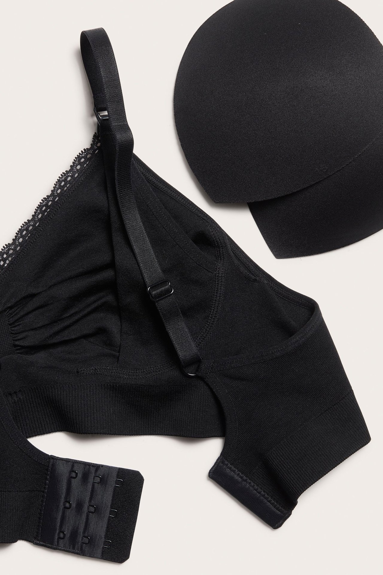 Zbliżenie czarnego bezszwowego biustonosza do karmienia z koronką, regulowanymi ramiączkami, zapięciem na haftki i wyjmowanymi wkładkami.