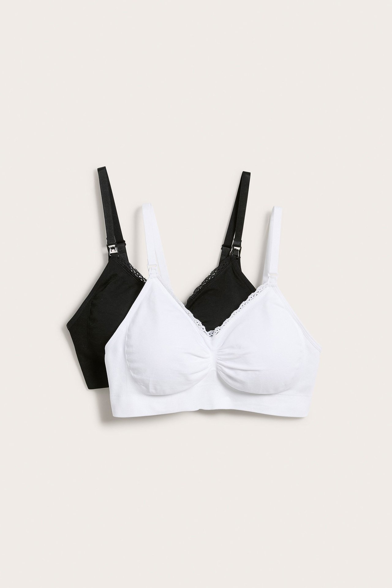 Framifrån: 2-pack sömlösa amningsbehåar, en vit och en svart, med spetskant.