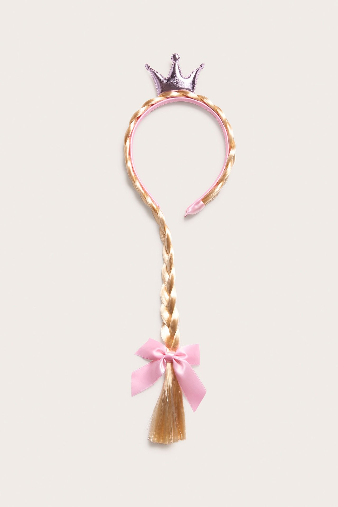 Ylhäältä kuvattu vaaleanpunainen hiuspanta, jossa on vaalea letti, vaaleanpunainen rusetti ja kiiltävä kruunu.