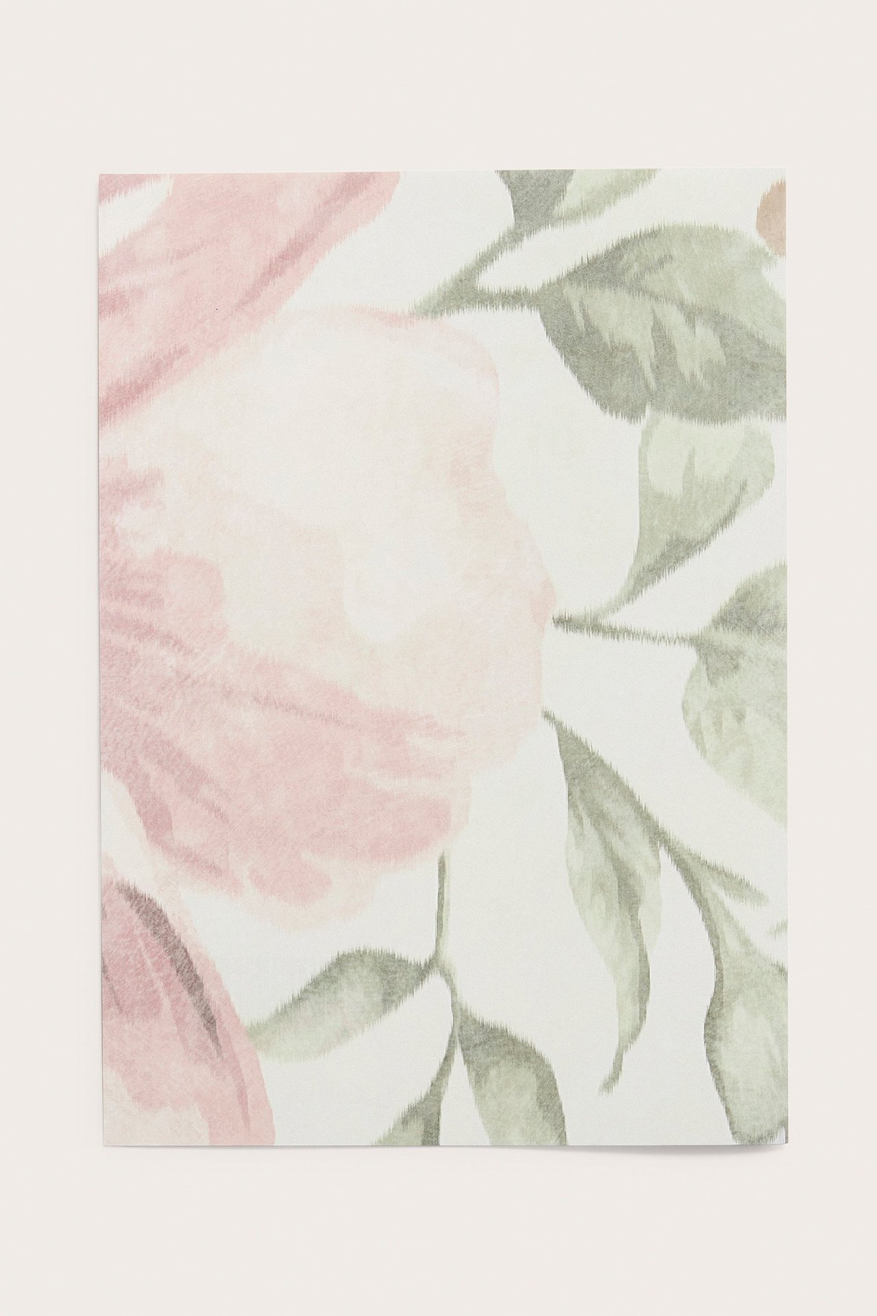 Närbild av ett beige tapetprov i papper med rosa och grönt blommönster.