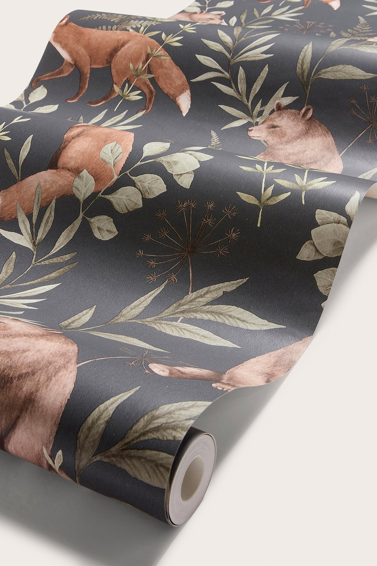 Närbild av en mörkblå tapetrulle med ett upprepat mönster av bruna rävar, björnar och gröna blad.