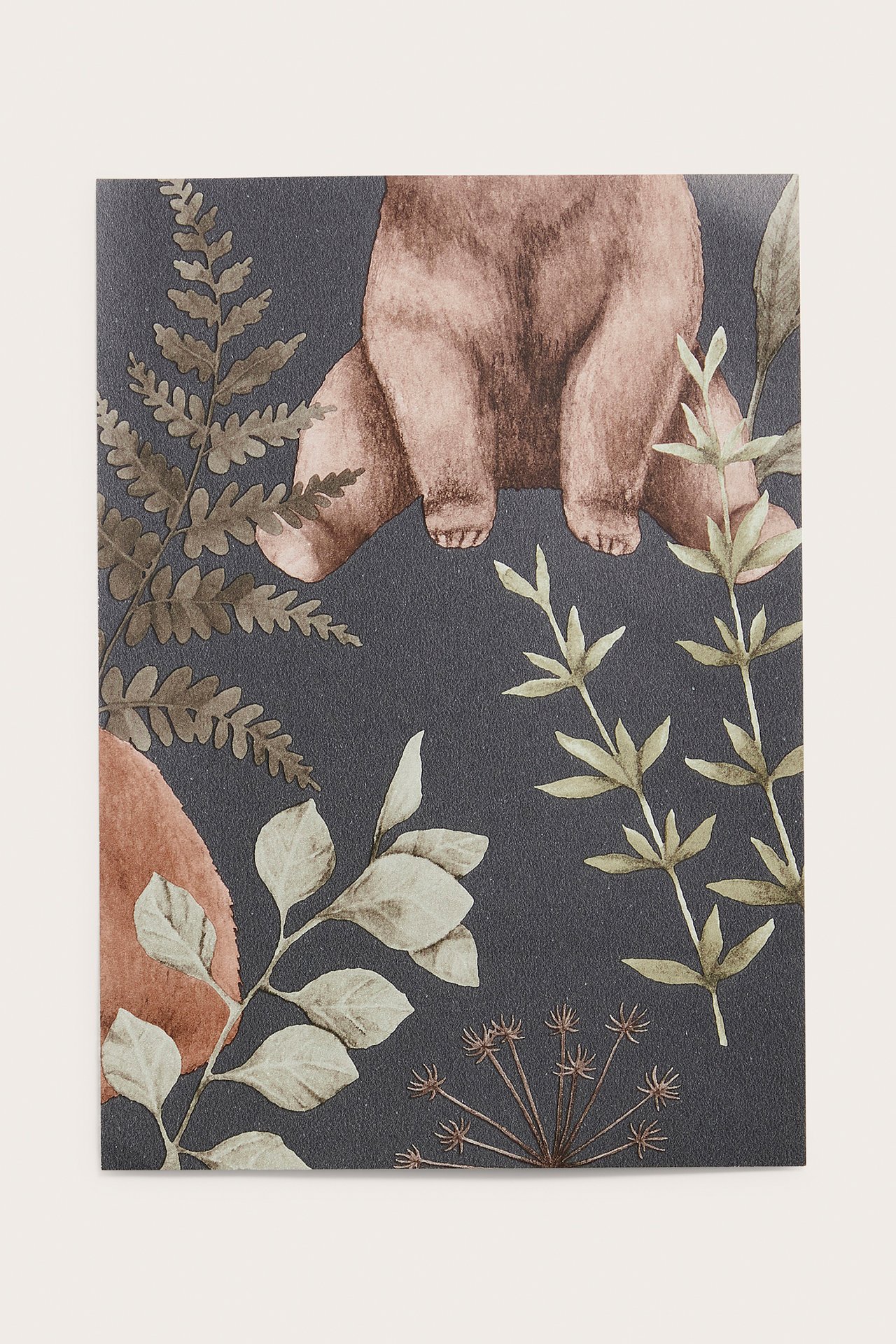 Nærbilde av en mørkeblå non-woven tapetprøve med mønster av brun bjørn og skogsmotiv.