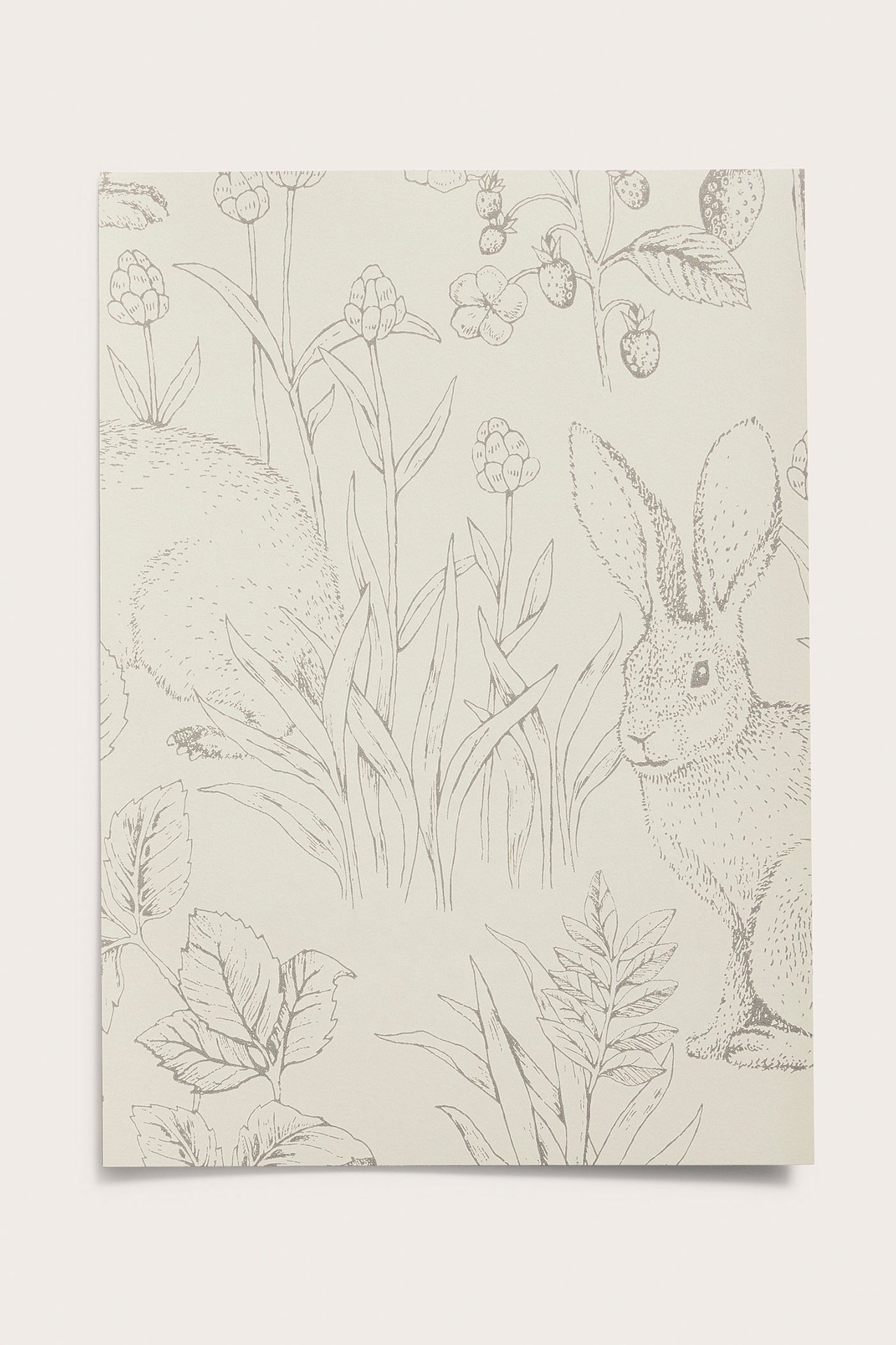 Beige tapetprøve, forfra, med strektegninger av kaniner, blomster og jordbær.