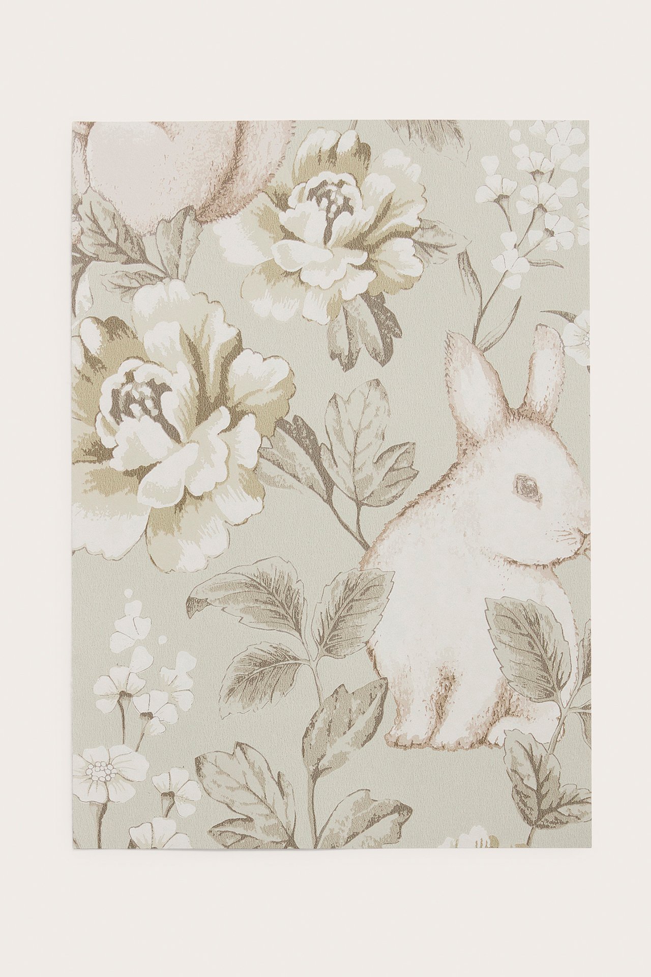 Nærbilde av en beige mønstret non-woven tapetprøve med kaniner og blomster.
