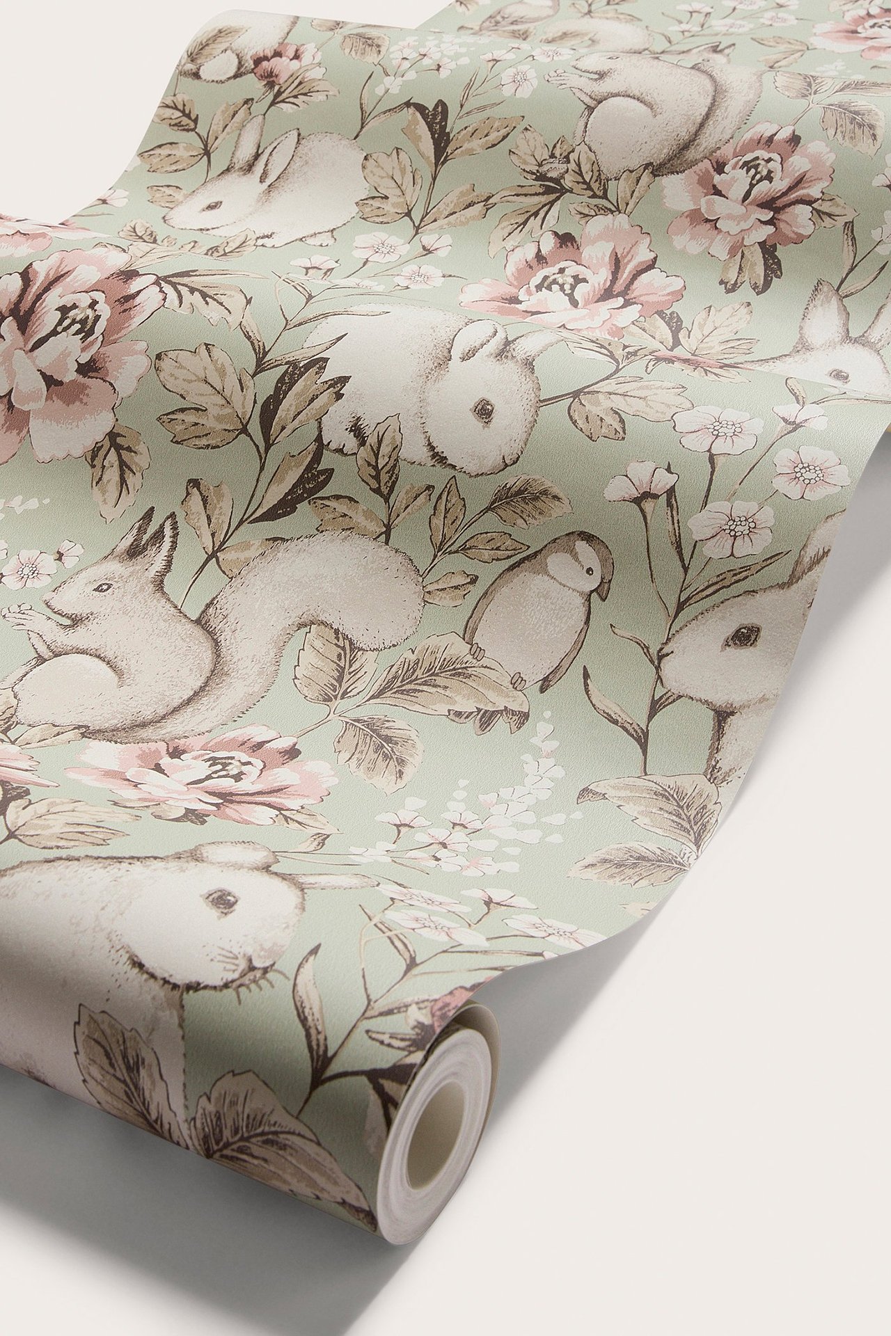 Nærbilde av grønn mønstret non-woven tapet med rosa blomster, kaniner, ekorn og fugler.