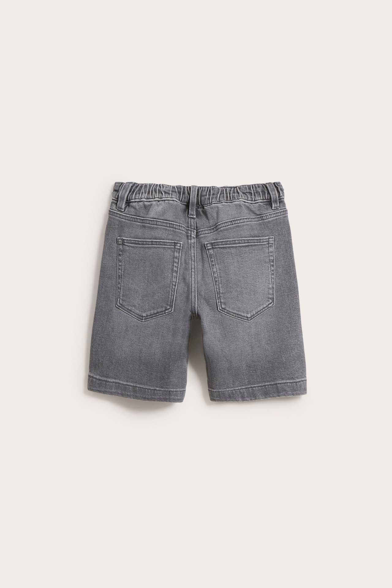 Bakifrån: barnens ljusgrå stretchiga denimshorts med resår i midjan och bakfickor.