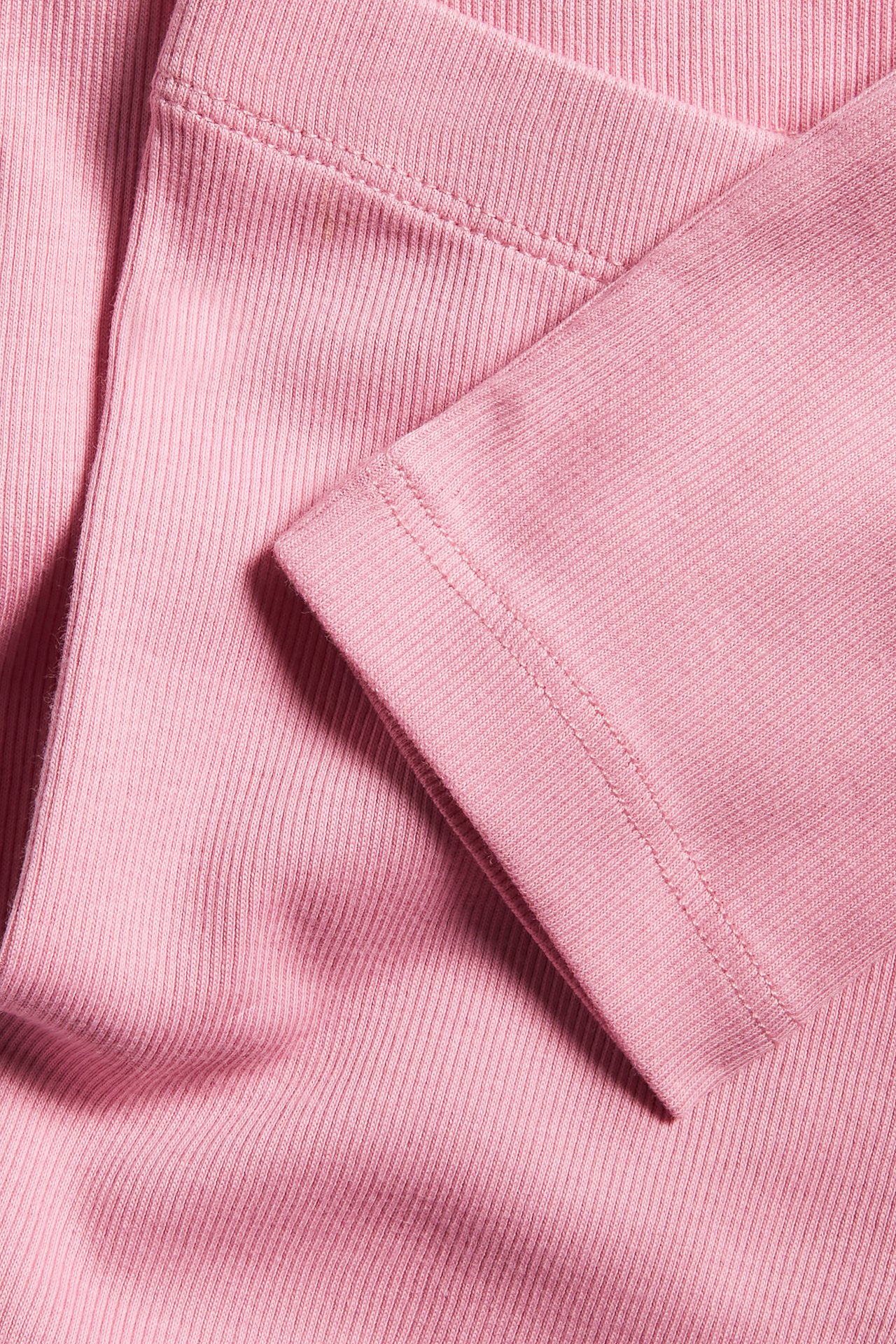 Närbild av rosa ribbade leggings med synliga sömmar.