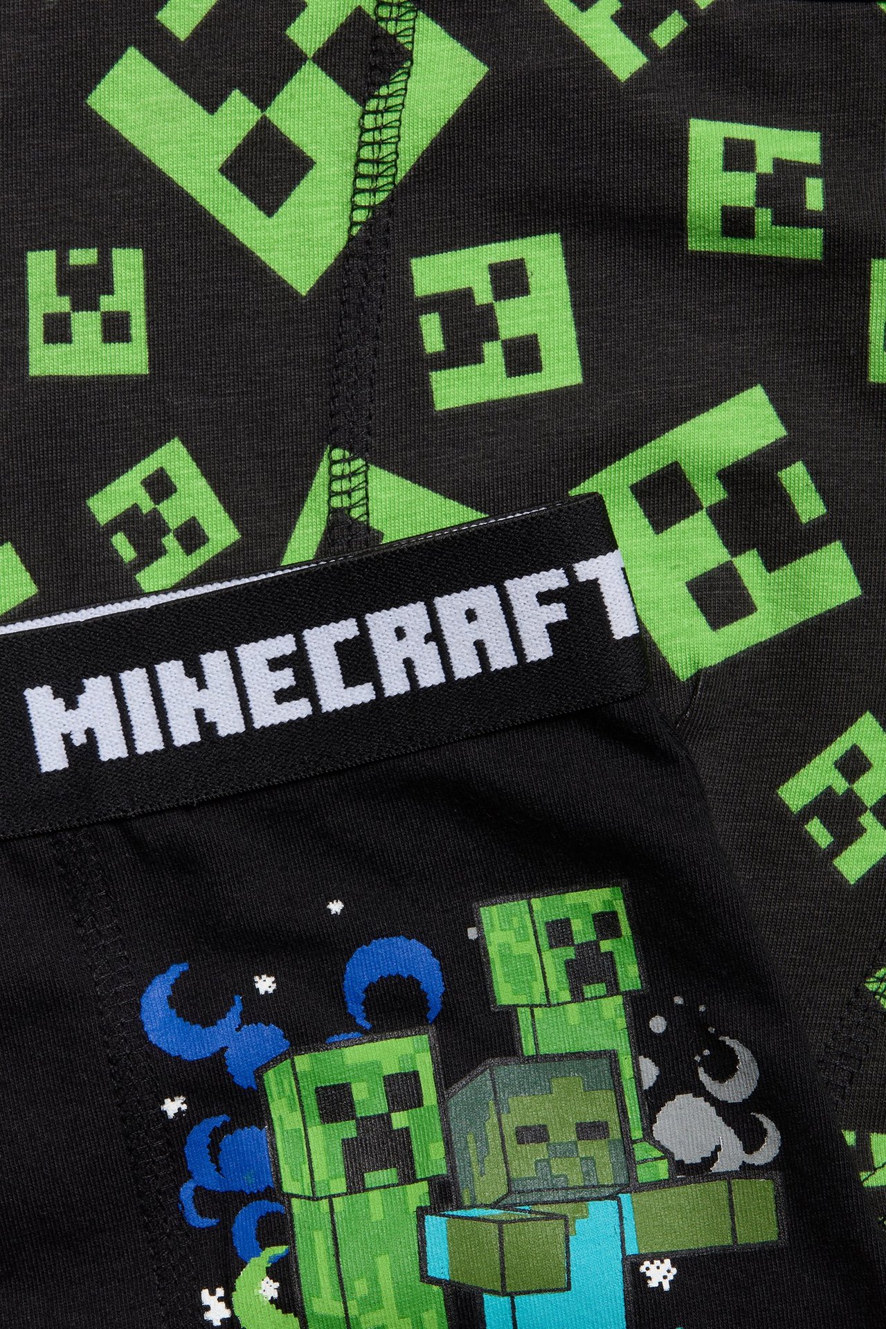 Zbliżenie na czarne bokserki dziecięce z zielonym wzorem Minecraft Creeper i białym napisem 'MINECRAFT' na pasie.