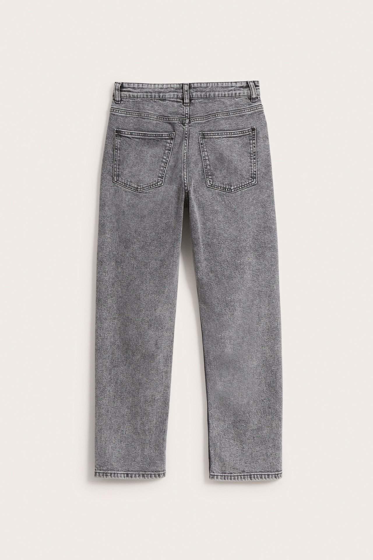 Bakifrån av gråa lösa mid-waist denimjeans med två bakfickor.
