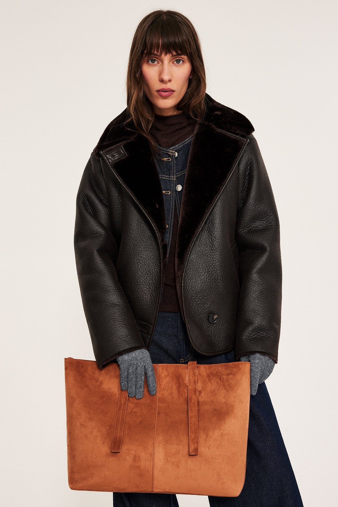 Szare rękawice z mieszanki wełny, kobieta ukazuje przód, melangowy wzór.