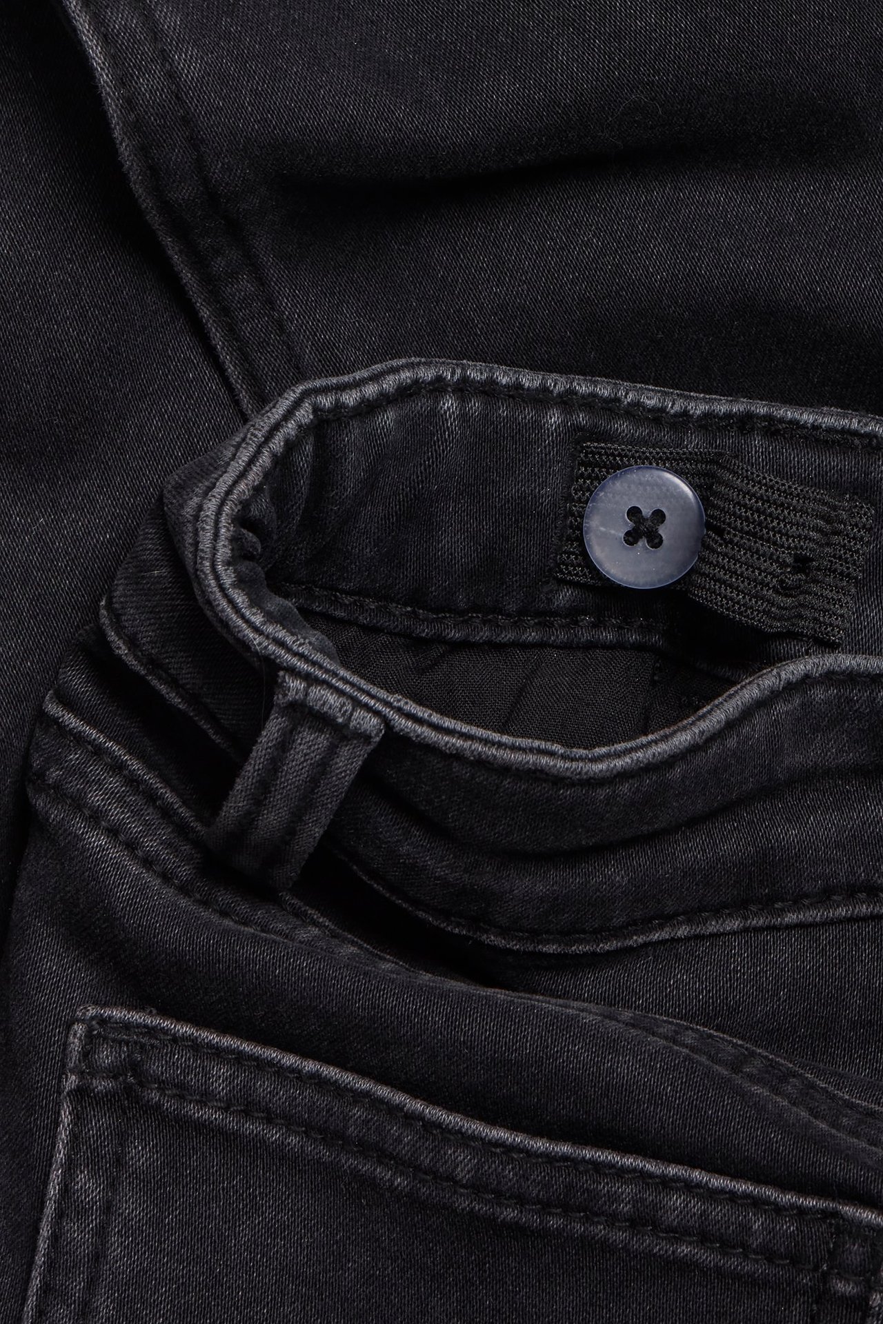 Zbliżenie na czarne dżinsy slim jogger denim z regulowaną elastyczną talią i guzikiem.
