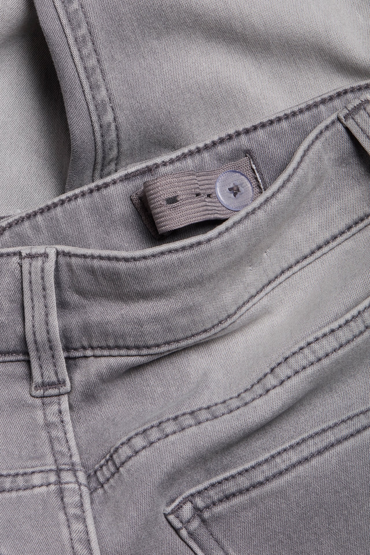 Närbild på barns gråa slim jogger denim jeanslinning med justerbar resår och knapp.