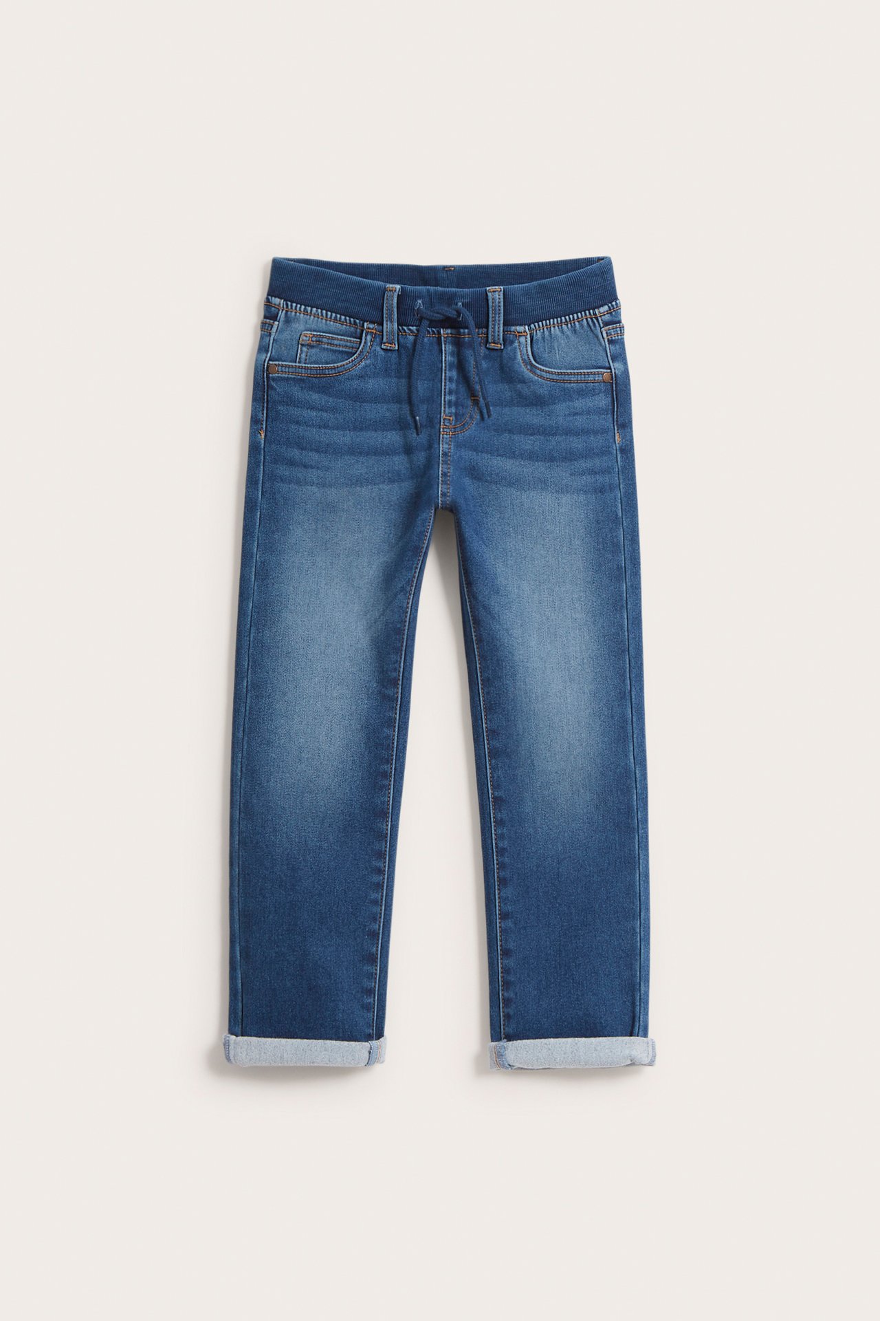 Frontvy av raka joggerjeans för barn i mörk denim med ribbad resårmidja och uppvikta benslut.
