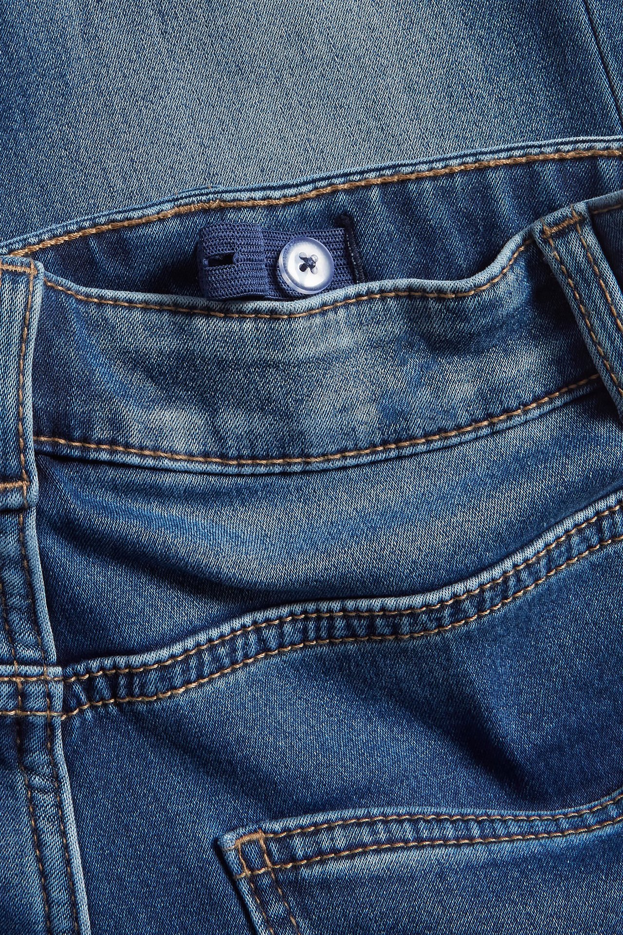 Zbliżenie na dziecięce niebieskie jeansy jogger denim z regulowaną talią i guzikiem.