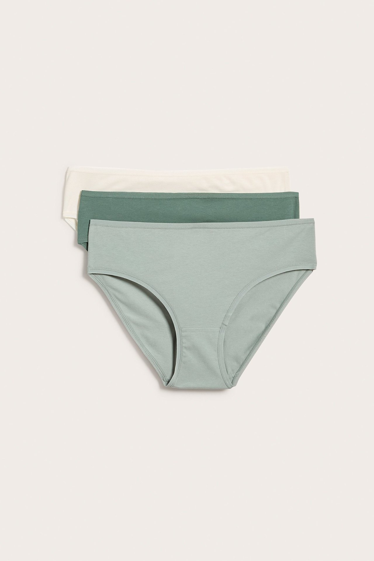 Widok z przodu trzech ułożonych gładkich bawełnianych majtek: jasnozielonych, ciemnozielonych i ecru.