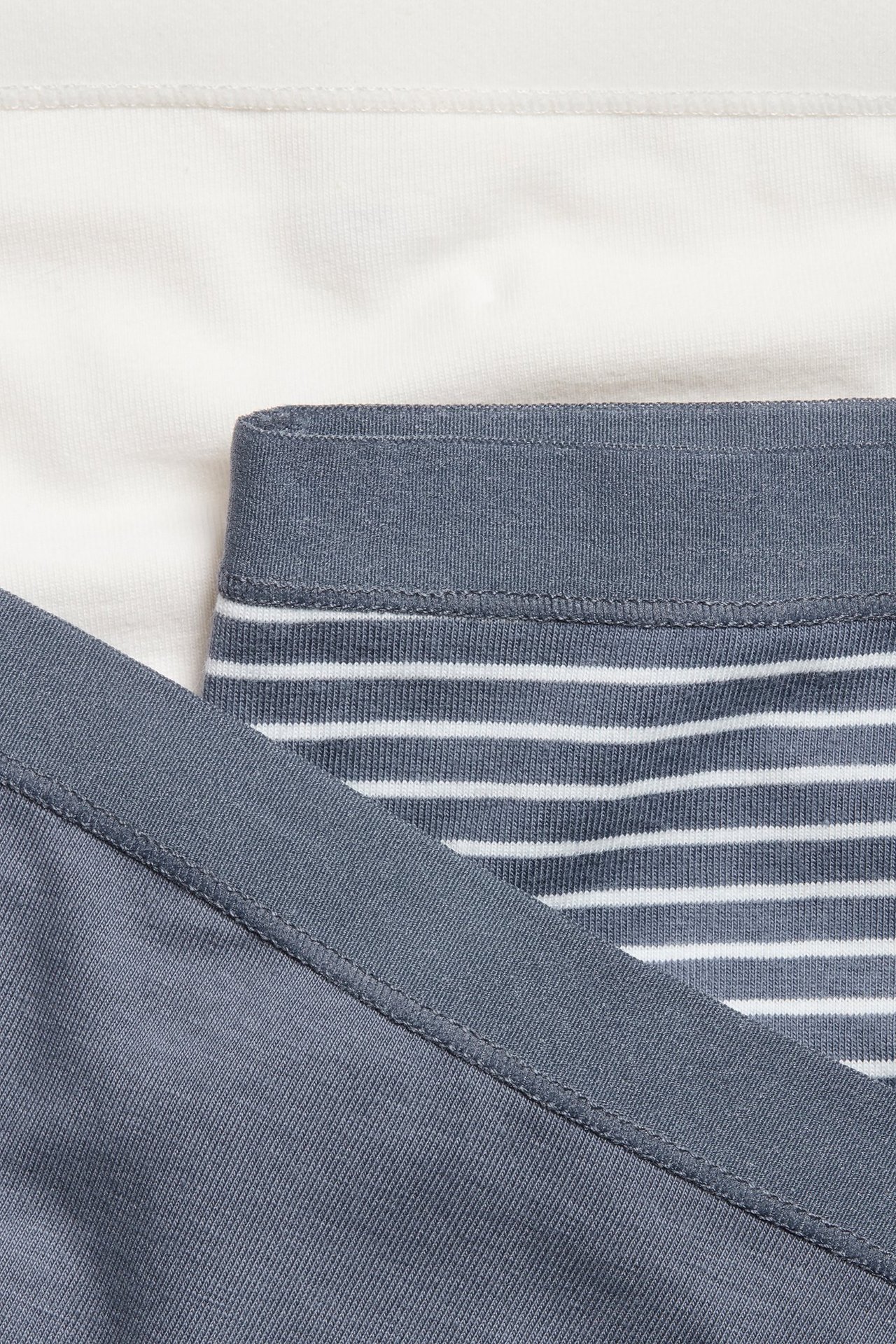 Zbliżenie na trzy damskie majtki z normalnym stanem: jedne ecru, jedne granatowe i jedne w paski.